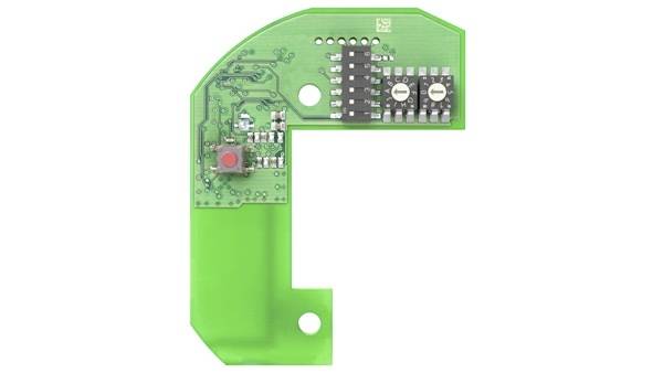 Grüne elektronische Leiterplatte mit einem roten Knopf und schwarzen Komponenten auf der oberen Seite.