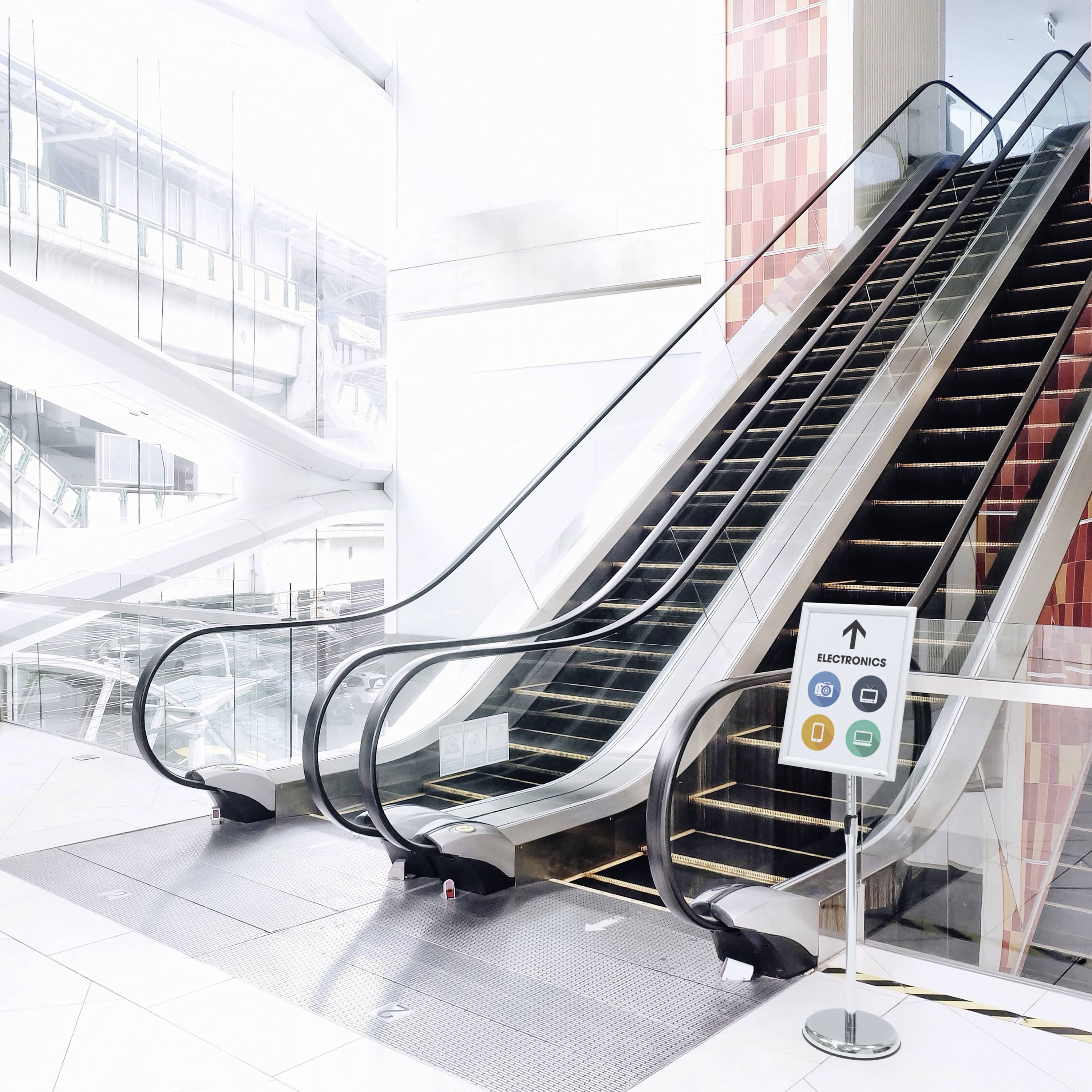 Eine Rolltreppe in einem modernen, hellen Einkaufszentrum. Ein Schild weist darauf hin, dass die Rolltreppe nicht in Betrieb ist.