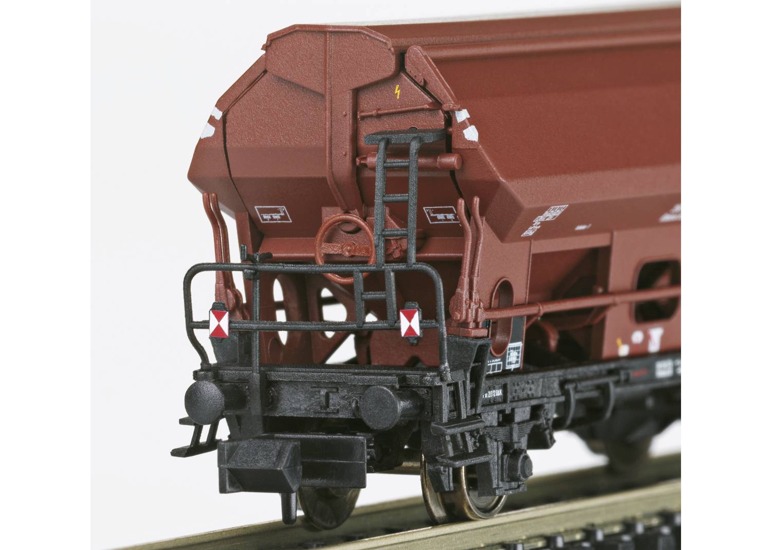 Ein brauner Güterwaggon mit Leiter und Sicherheitszeichen auf einem Gleis. Detailliertes Modell eines Bahnwaggons für Modellbahnen.