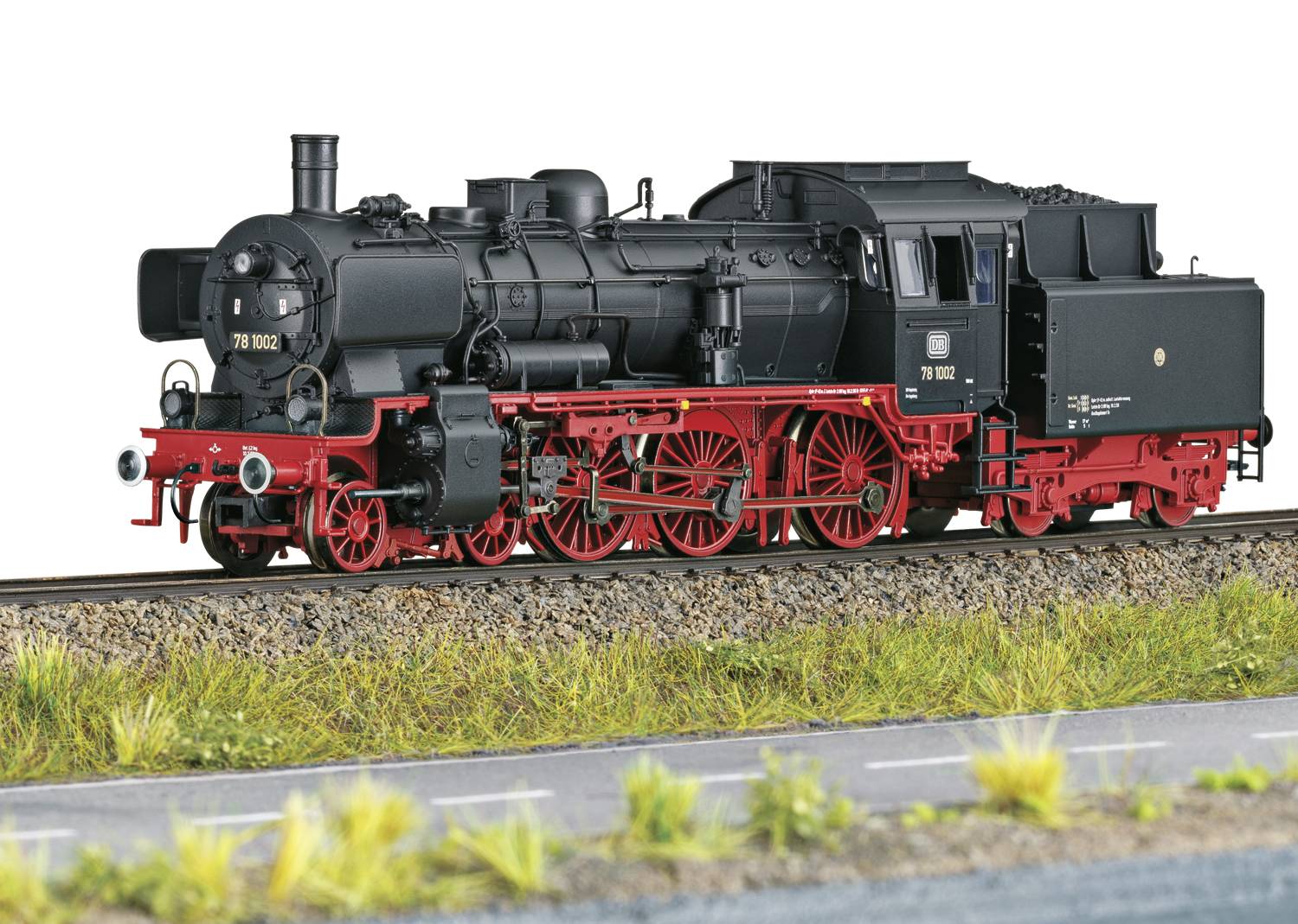 Schwarze Dampflokomotive mit roten Details und Rädern fährt auf Bahngleisen. Die Lokomotive zeigt historische Technik und Design.