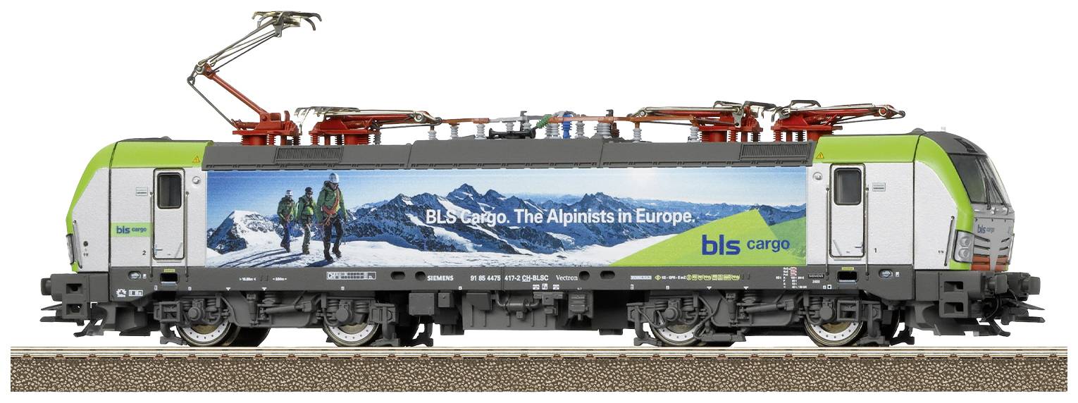 Eine Modelllokomotive mit einem Werbeslogan für 'BLS Cargo' auf der Seite. Das Bild zeigt eine gebirgige Landschaft und Wanderer.