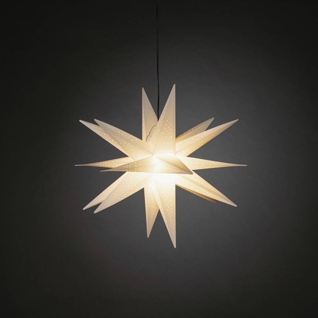 Ein beleuchteter, weißer Papierstern mit perforierten Mustern hängt vor einem dunklen Hintergrund und strahlt warmes Licht aus.