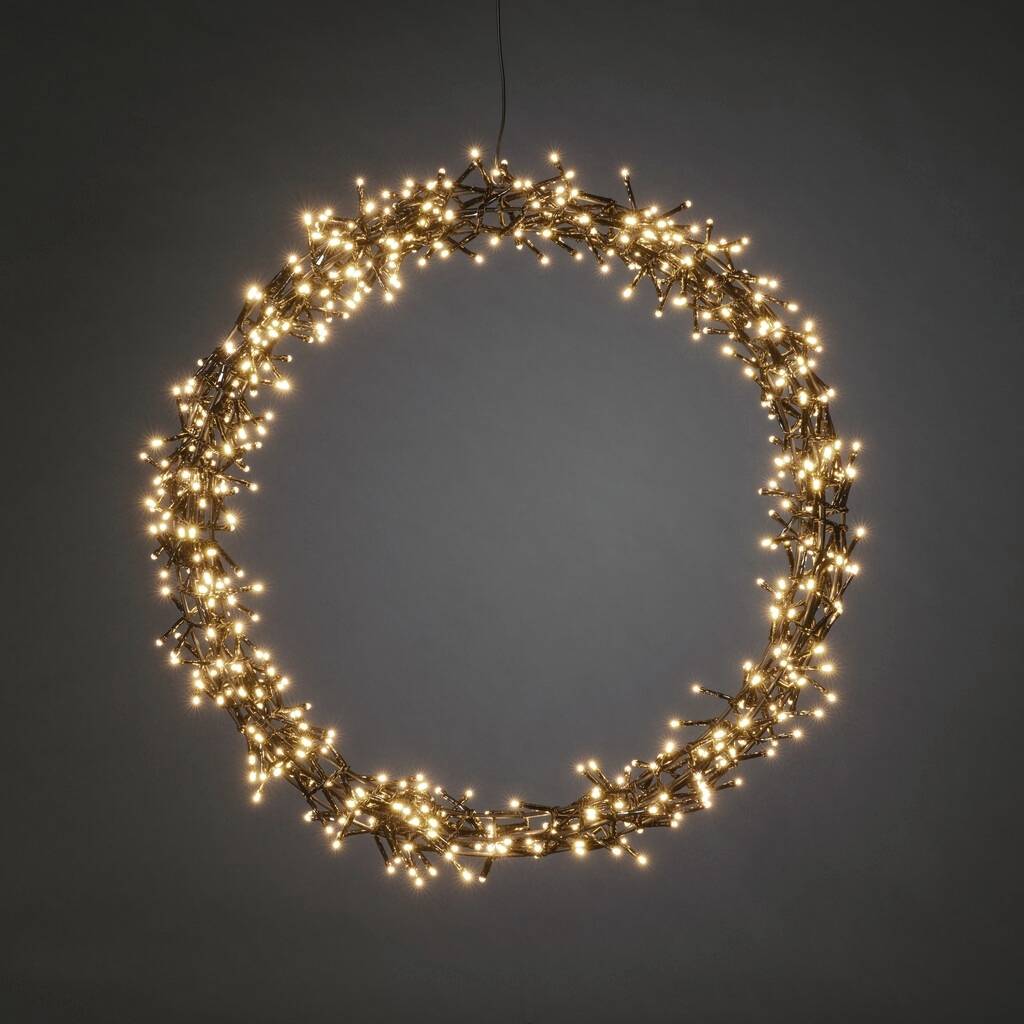 Ein leuchtender, runder Lichterkranz mit vielen kleinen, warmweißen Lichtern hängt vor einem neutralen Hintergrund.