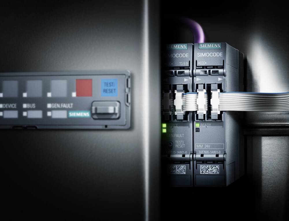 Nahaufnahme eines Schaltschrankes mit elektrischen Komponenten und Kabelverbindungen, darunter Siemens SIMOCODE Module mit LED-Anzeigen.