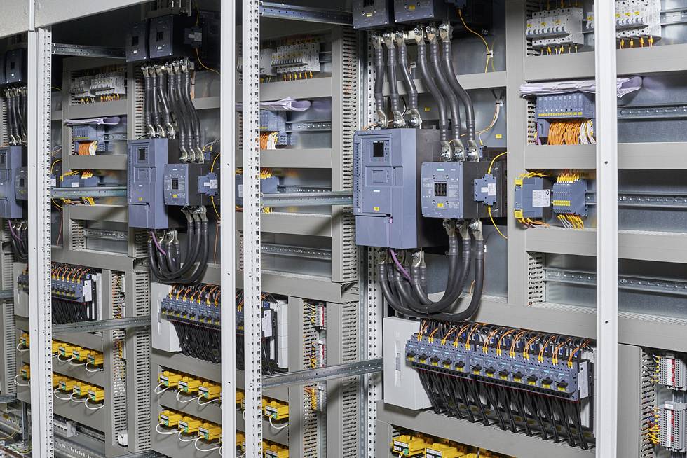 Ein Schaltschrank voller Kabel und elektrischer Komponenten, mit mehreren Schaltkreisen und Anschlüssen, zeigt komplexe Verkabelung.