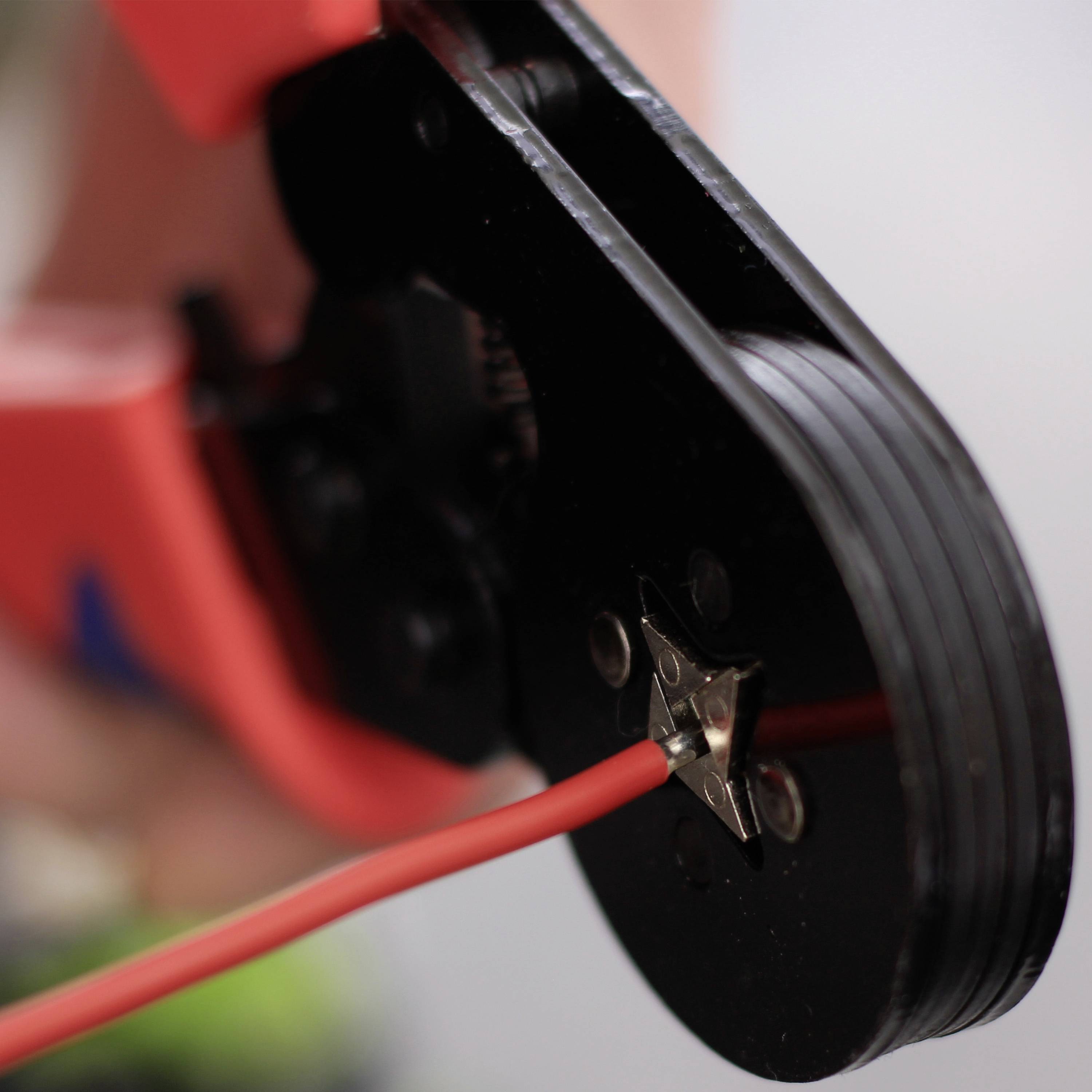 Nahaufnahme einer roten Crimpzange, die einen Metallverbinder an ein rotes Kabel anbringt. Werkzeug wird zum Verbinden von Drähten verwendet.