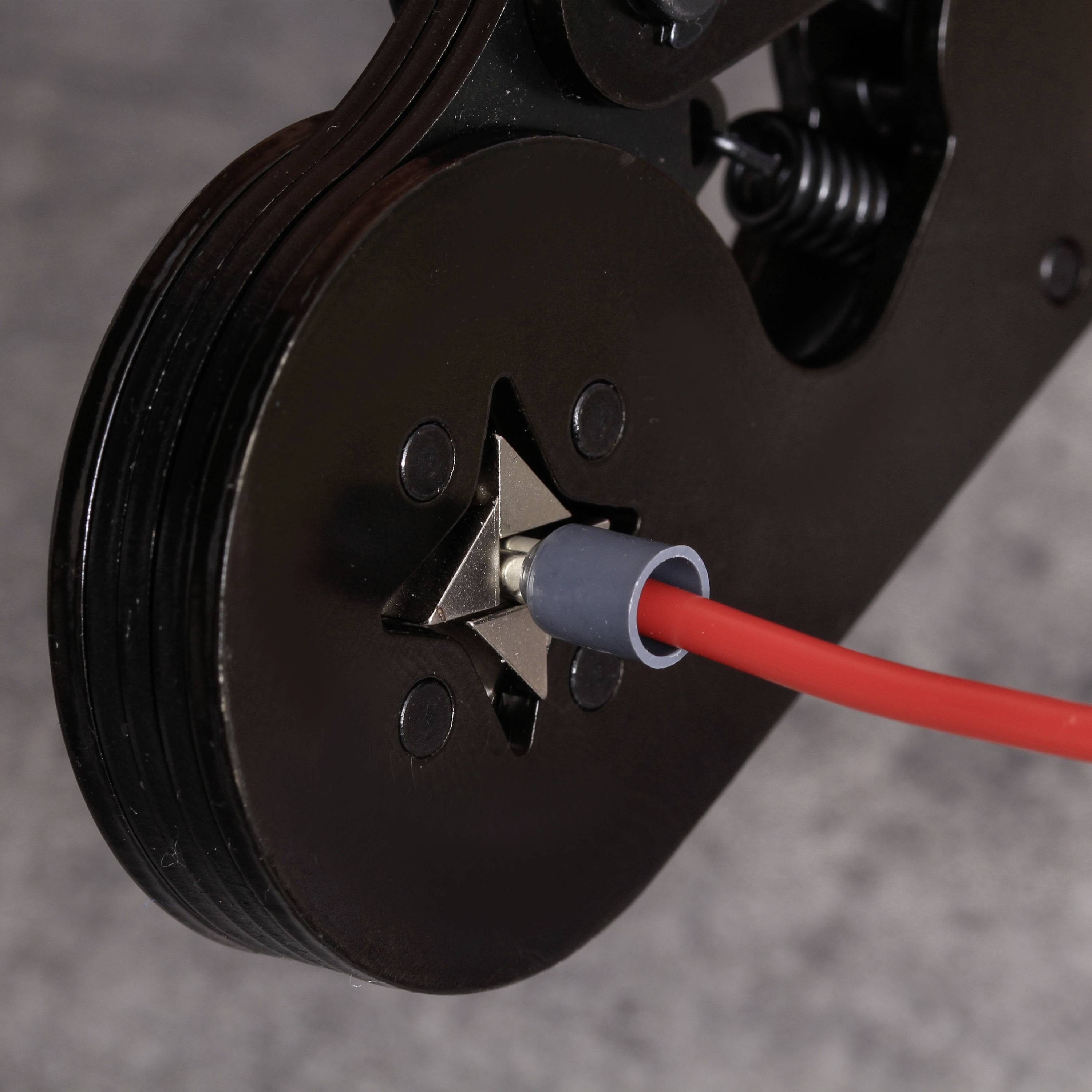 Nahaufnahme eines schneidenden Werkzeugs mit einem roten Draht dazwischen, gezeigt auf einem grauen Hintergrund.