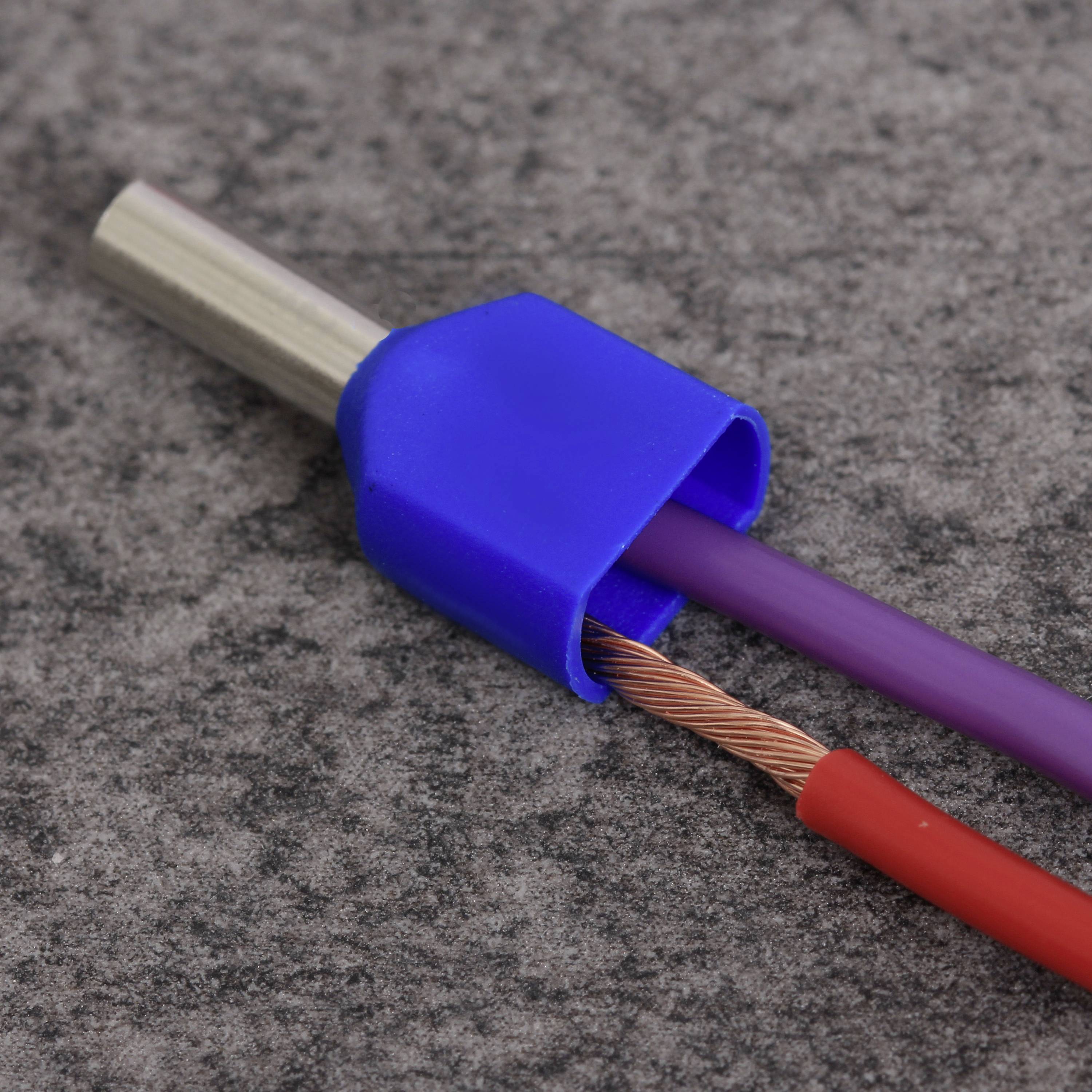 Elektrisches Kabel mit einem blauen Kunststoffanschluss, das ein freigelegtes Kupferdrahtende zeigt, auf grauem Hintergrund.