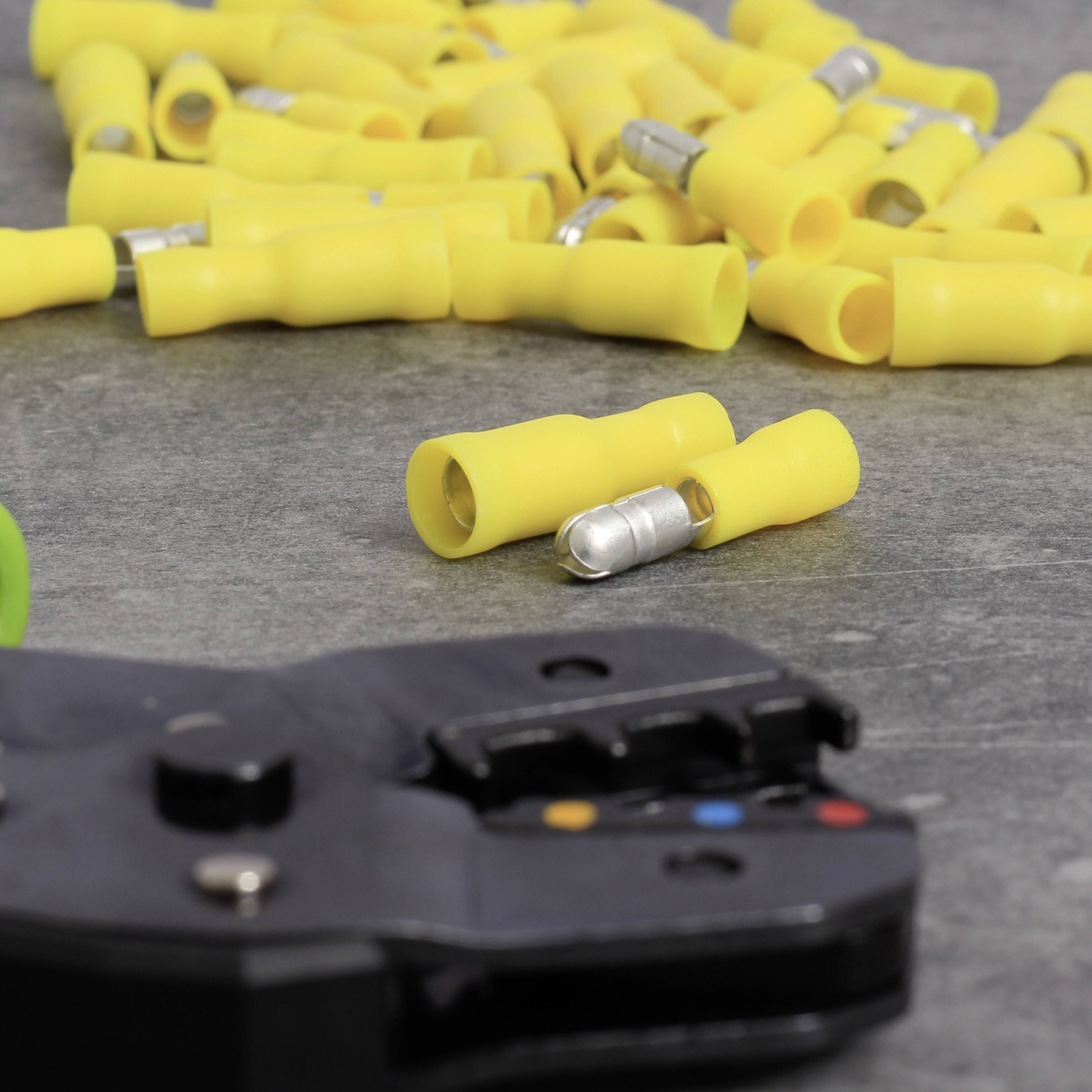 Gelbe Crimpverbinder verteilt auf einem Tisch mit einer Crimpzange im Vordergrund. Eignen sich für elektrische Verbindungen.