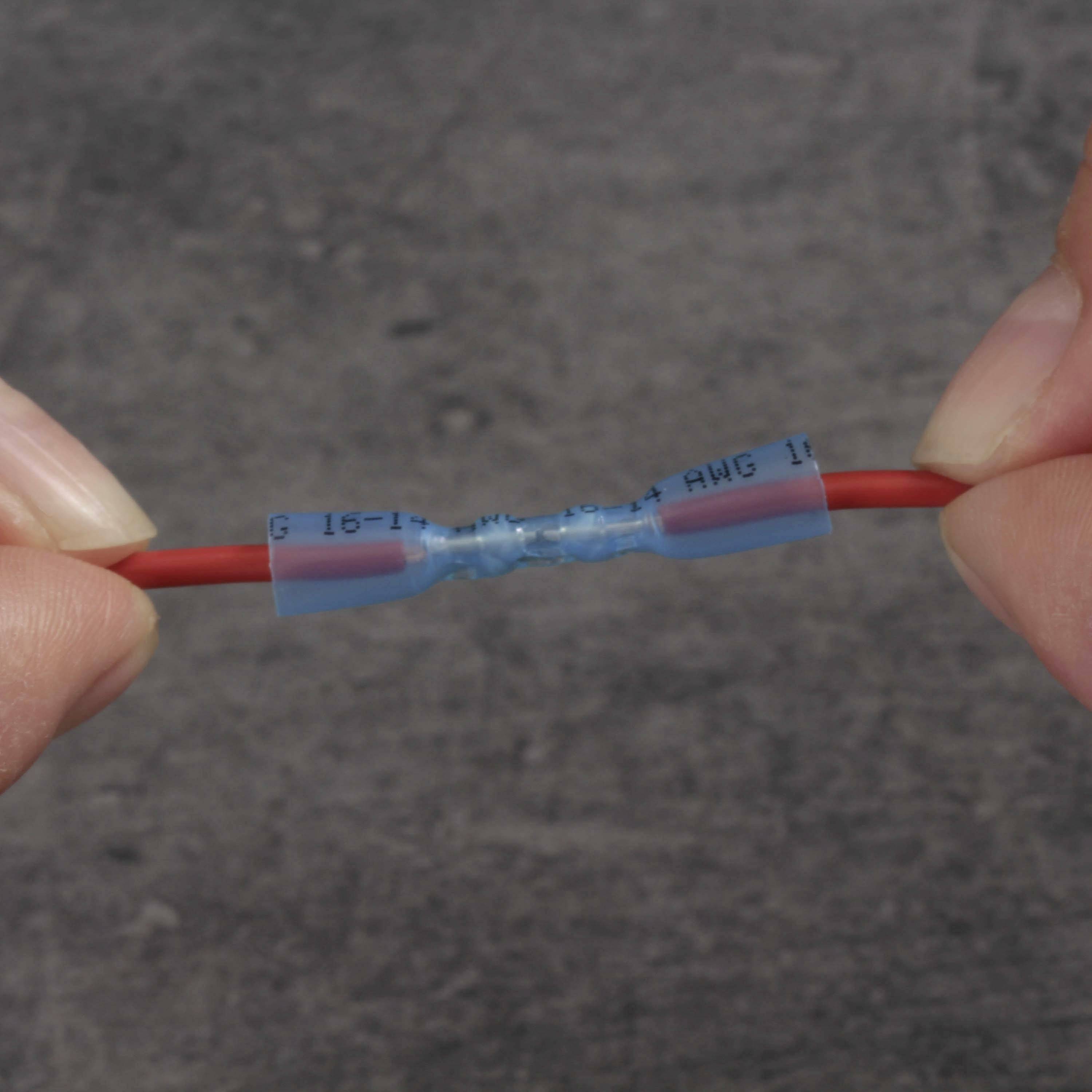 Zwei Hände halten ein elektrisches Kabel, das an einem blauen Stoßverbinder verbunden ist, um Drahtverbindungen zu sichern.