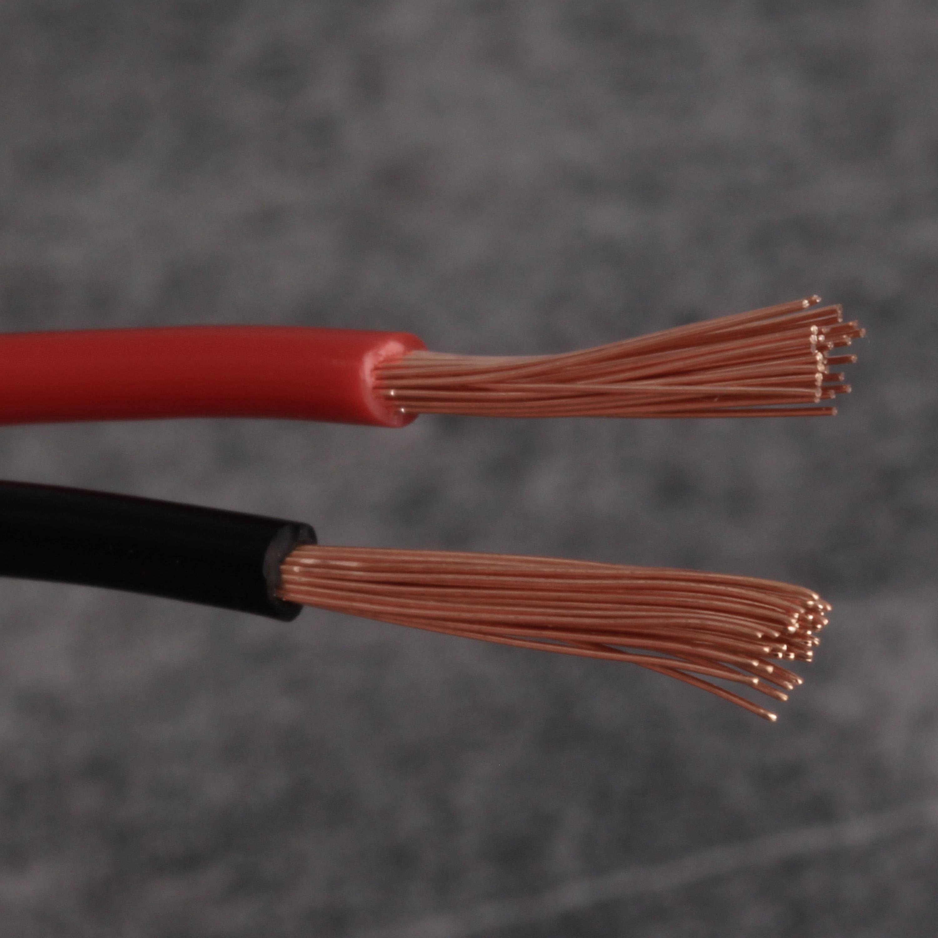 Zwei offene Elektrokabel: eines rot, eines schwarz, mit freigelegten Kupferdrähten am Ende, auf einem neutralen Hintergrund.
