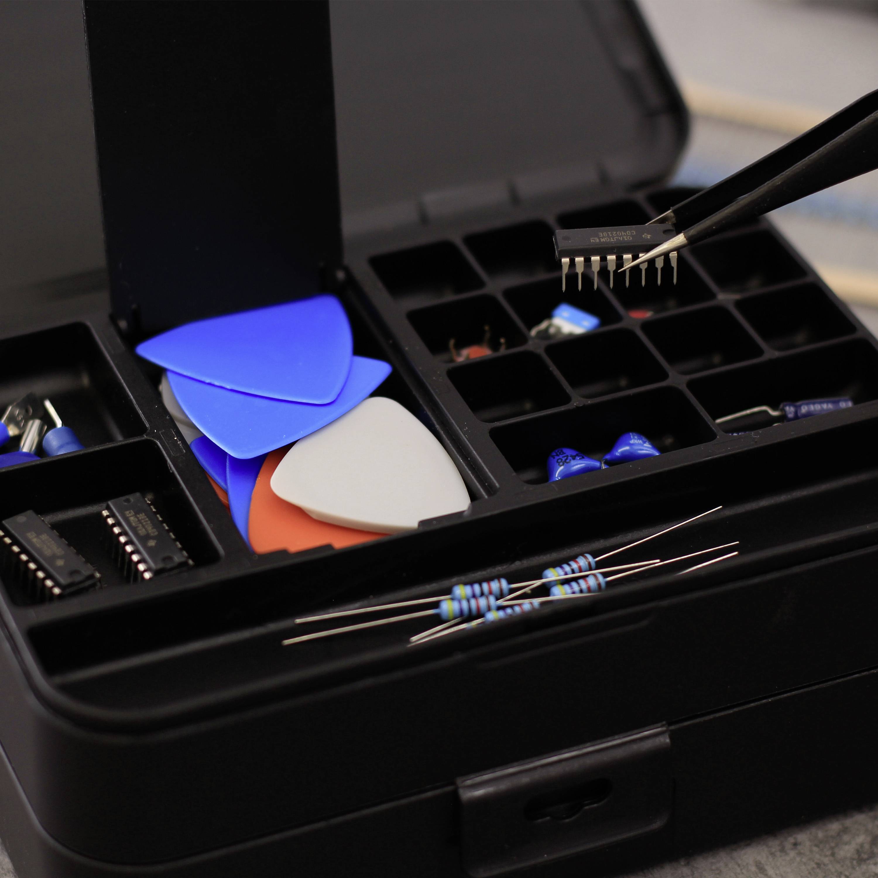 Elektronikteile in einem Organizerkasten, einschließlich Widerstände, Mikrocontroller, Plektren und LEDs, mit einer Pinzette.