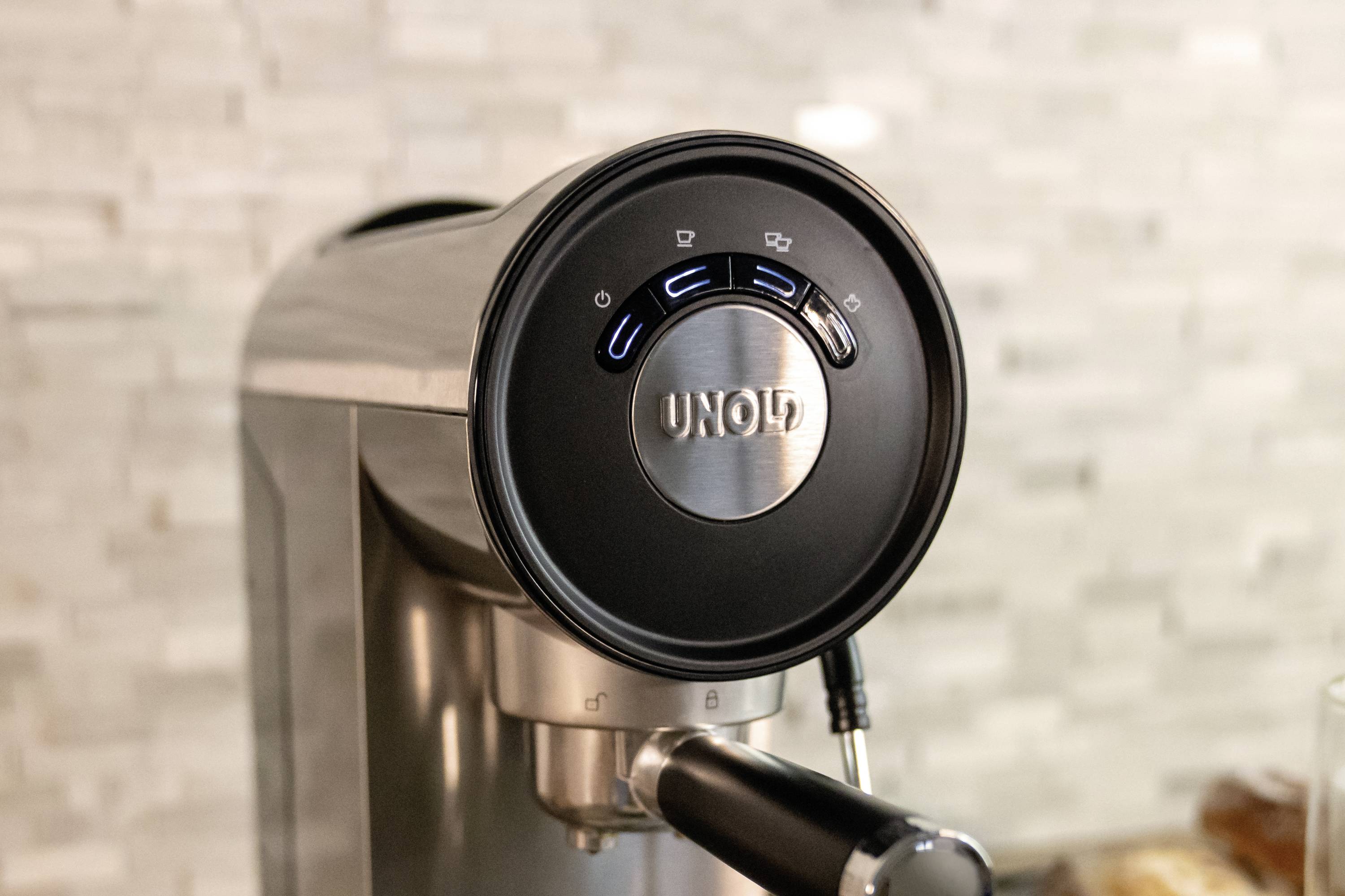 Kaffeemaschine in modernem Design mit sichtbarer Kontrollleiste und silbernem Gehäuse, auf Küchenarbeitsplatte platziert.