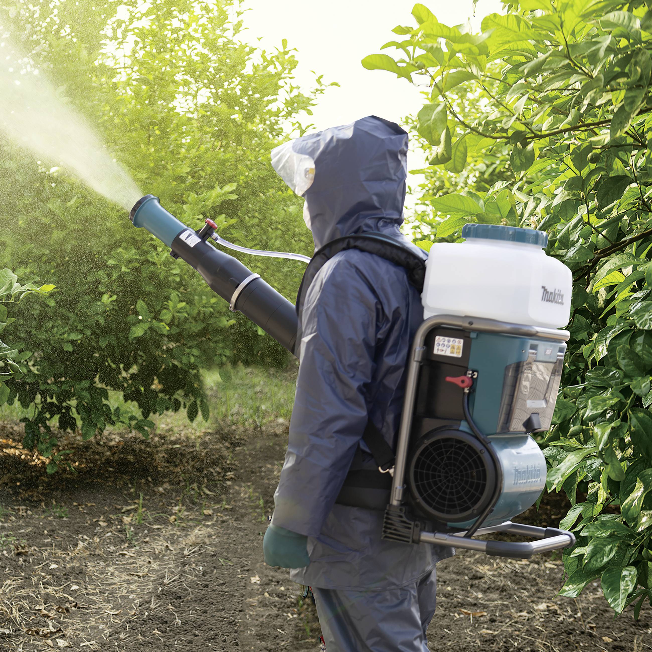 Eine Person sprüht Pestizide auf Obstbäume. Sie trägt einen Schutzanzug und eine Atemmaske, um sich vor Chemikalien zu schützen.