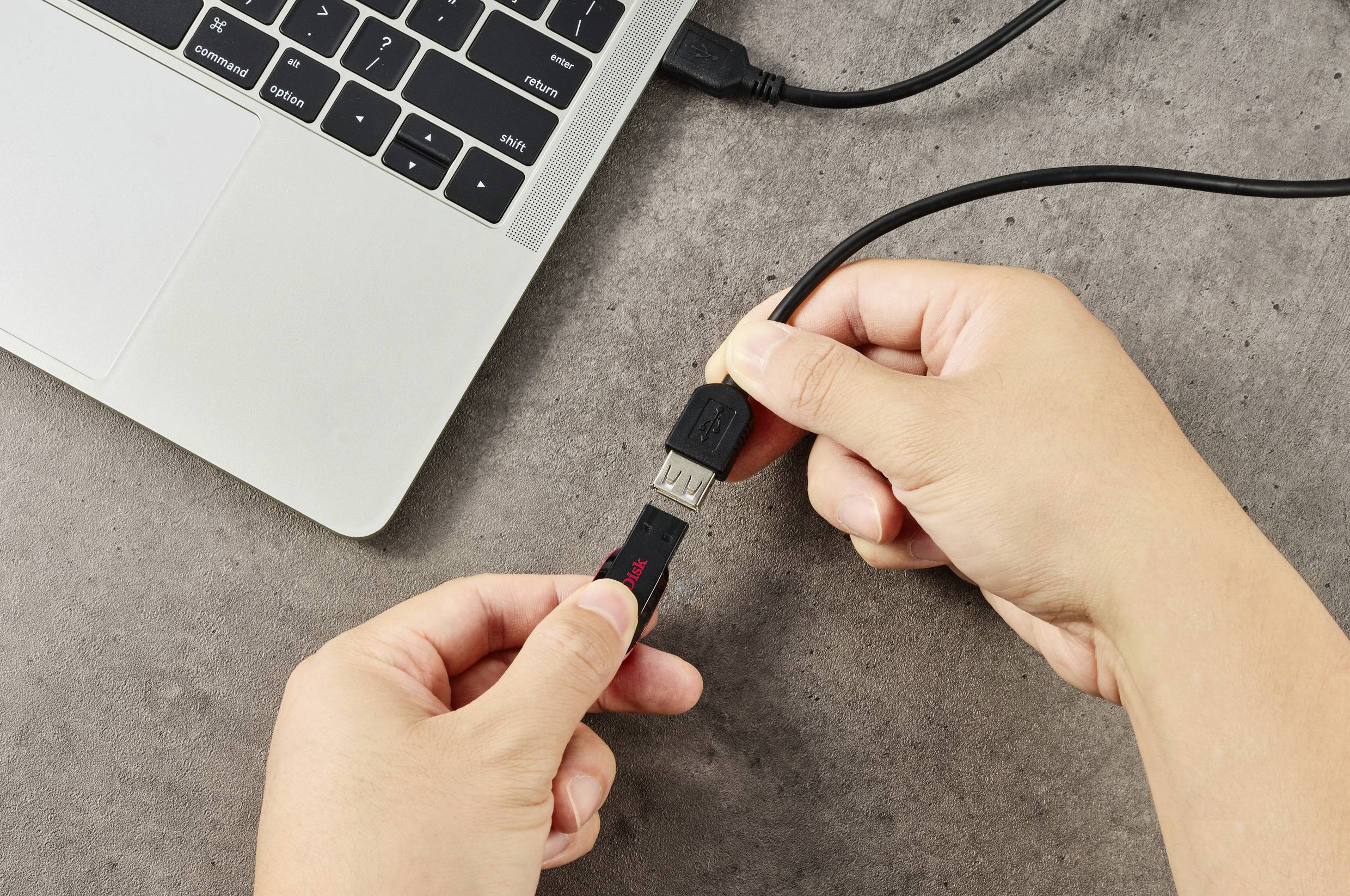 Eine Hand steckt ein USB-Kabel in einen Laptop.