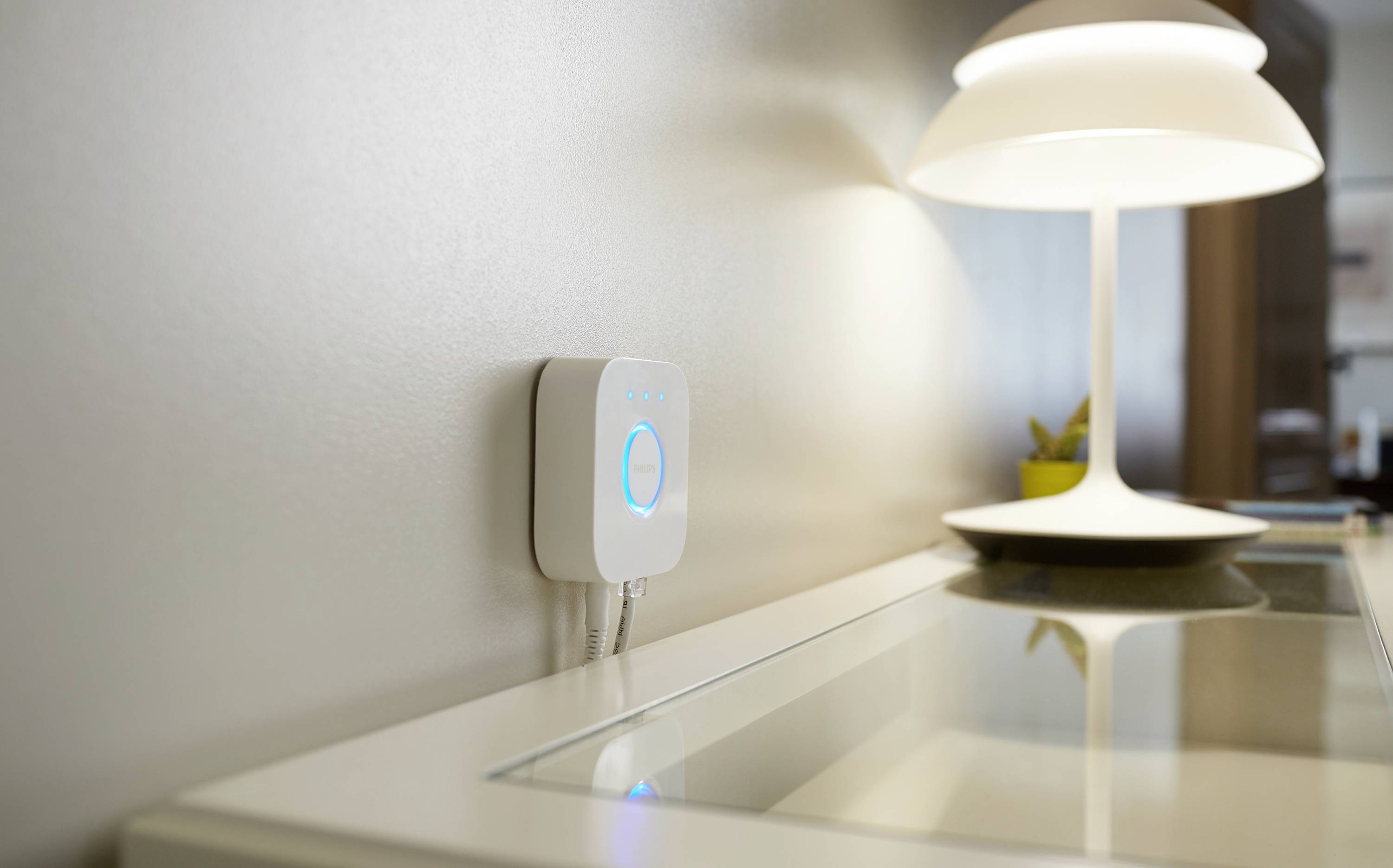 Ein weißer WLAN-Router leuchtet blau und ist an einer Wand neben einem weißen Tisch mit Lampe angebracht. Die Szene wirkt modern.