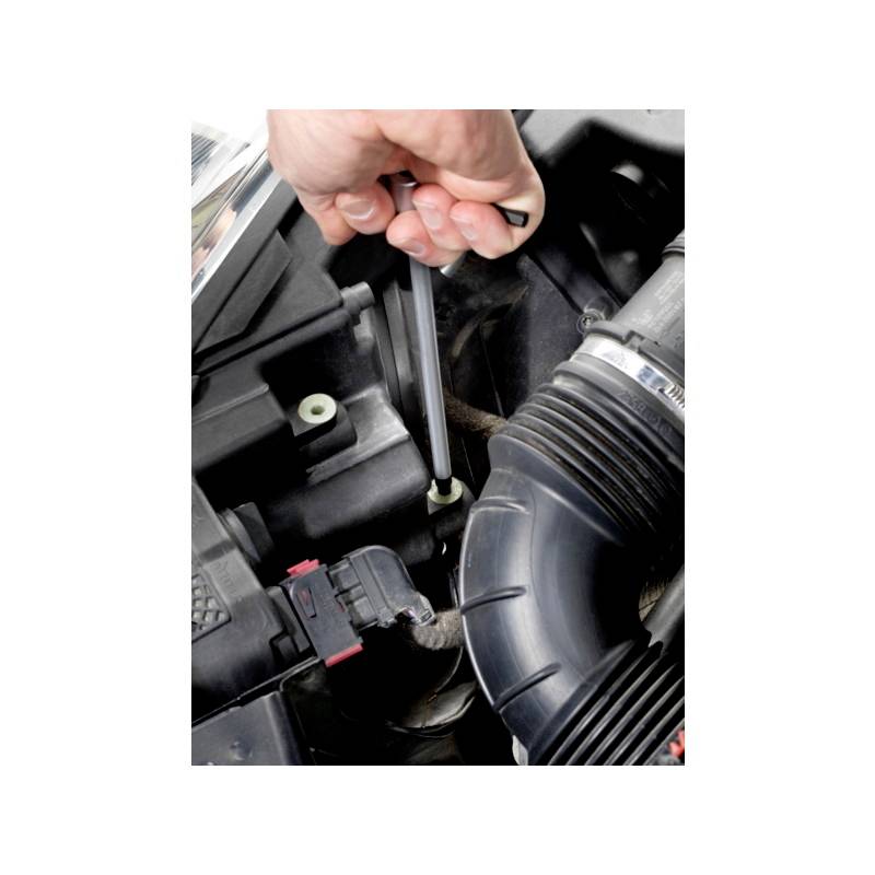 Eine Person benutzt einen Schraubendreher, um eine Schraube im Motorraum eines Autos zu befestigen.