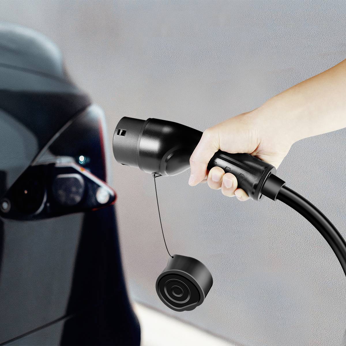Eine Hand hält ein Ladekabel in Richtung eines Elektrofahrzeug-Ladeanschlusses. Dies zeigt den Ladeprozess eines Elektroautos.