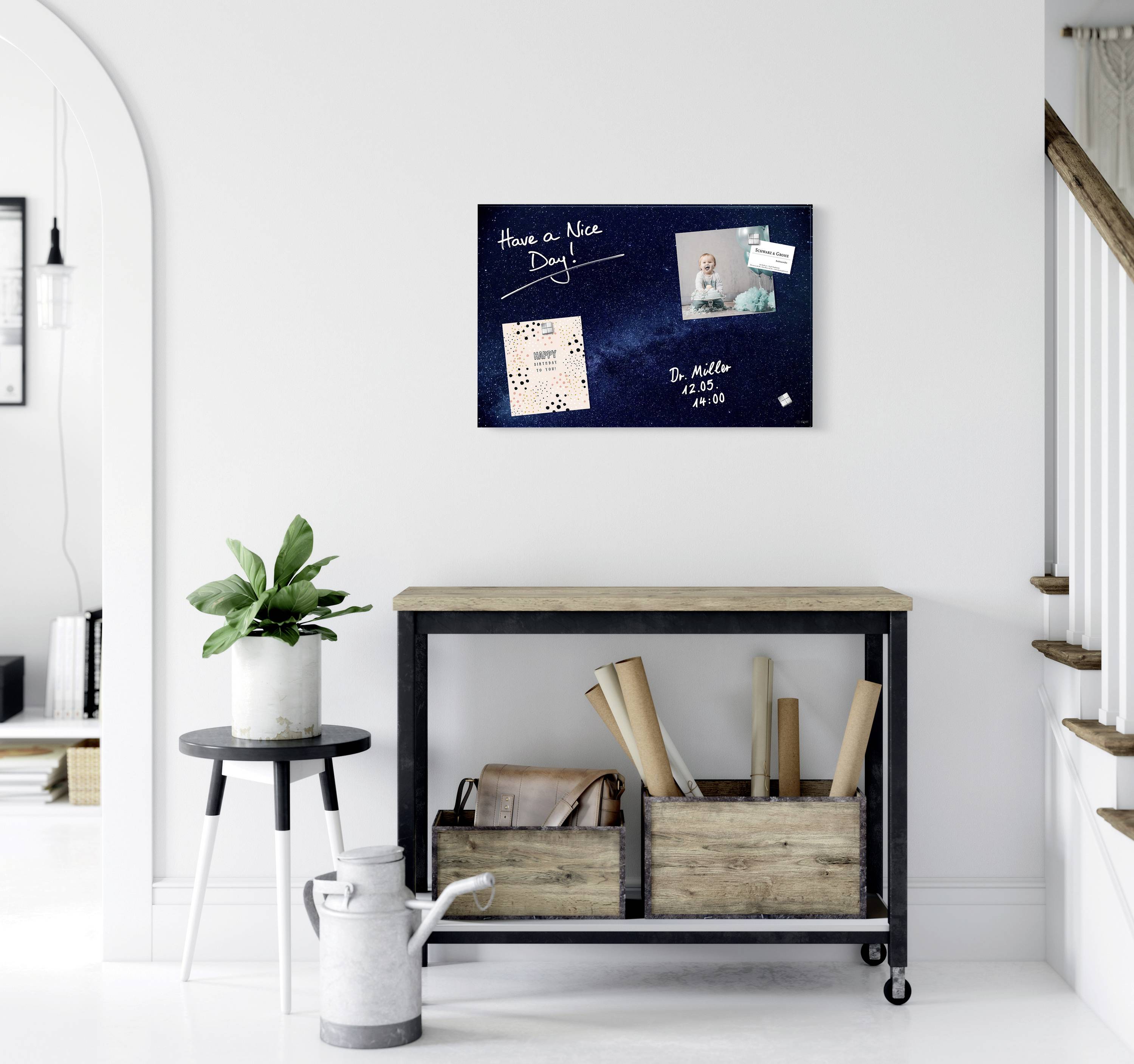 Eine Pinnwand mit der Aufschrift 'Have a Nice Day', Bildern und einer Notiz. Darunter ein Tisch mit Pflanzen und Aufbewahrungsboxen.