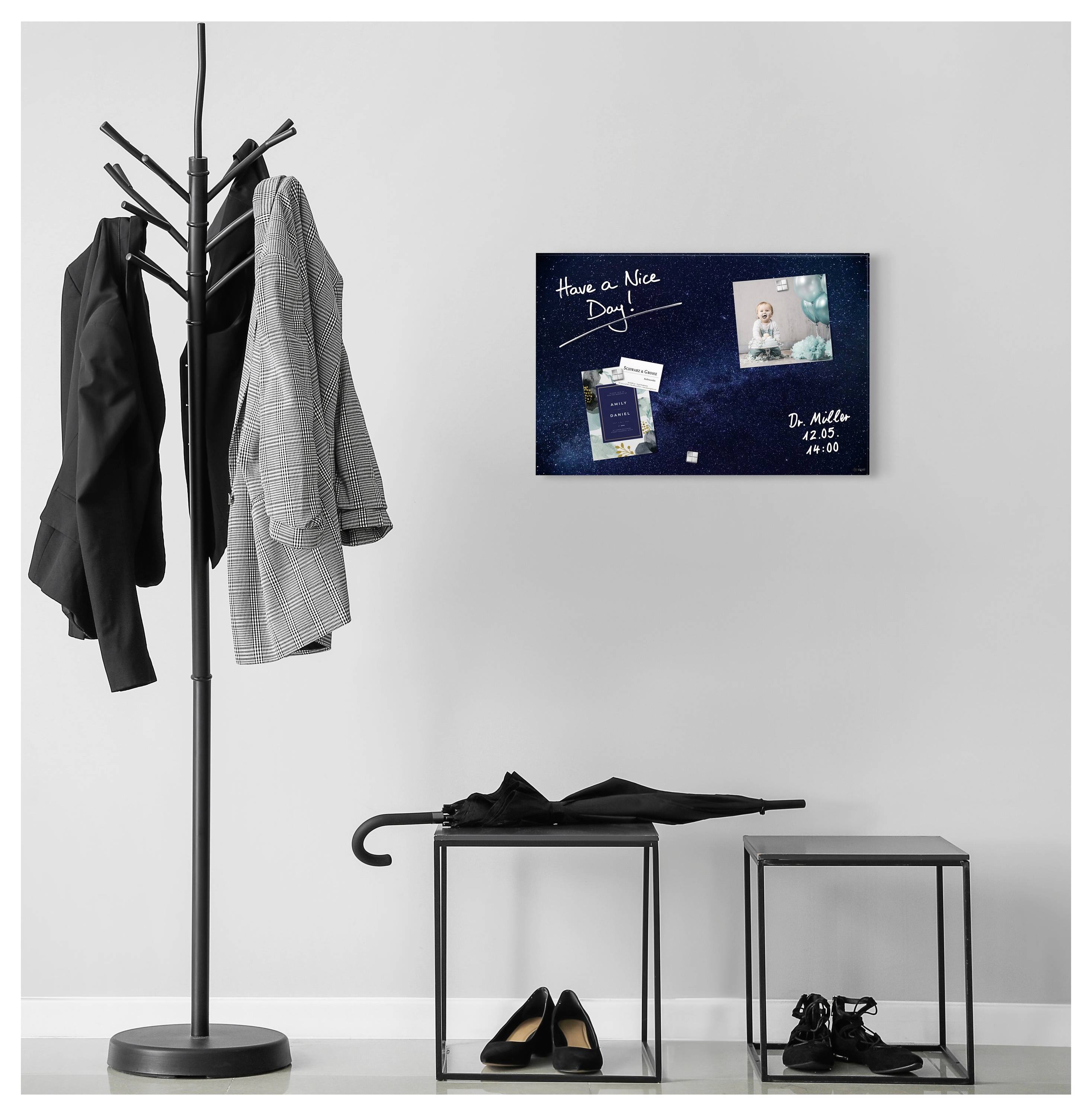 Minimalistischer Eingangsbereich mit einer Garderobe, die Jacken hält, zwei Beistelltischen mit Regenschirm, Schuhen und einer Wandtafel mit der Aufschrift „Einen schönen Tag noch!" mit Fotos.