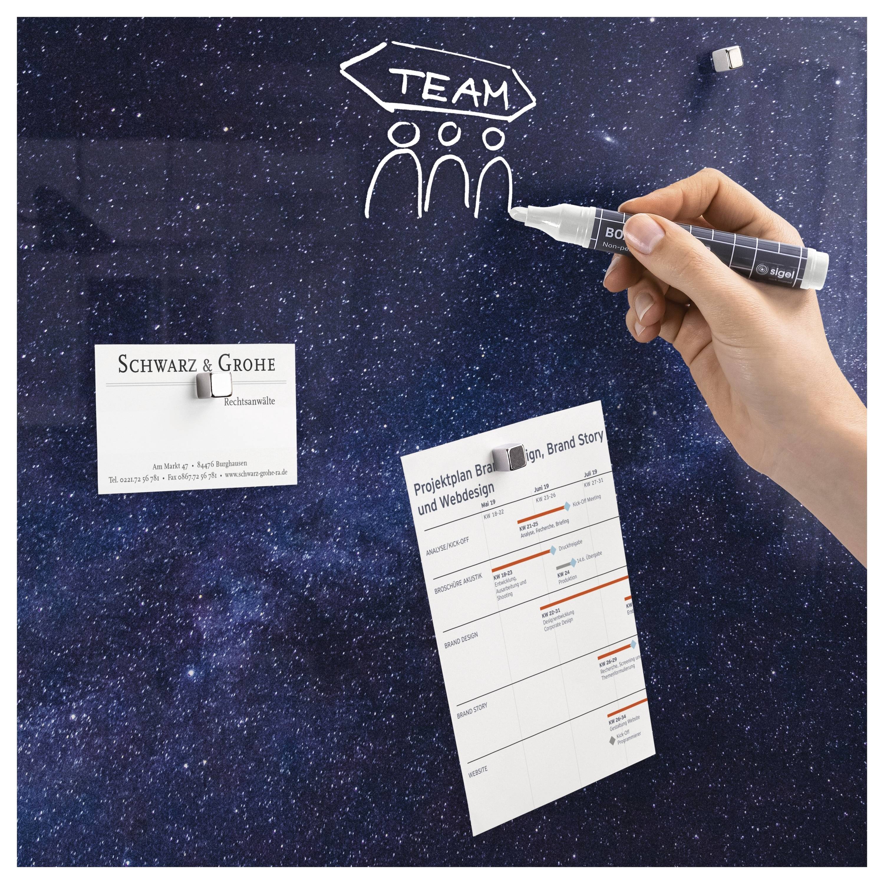 Handzeichnung von „TEAM" über drei Personensymbolen auf einer Tafel mit Sternen, darunter zwei angeheftete Visitenkarten.