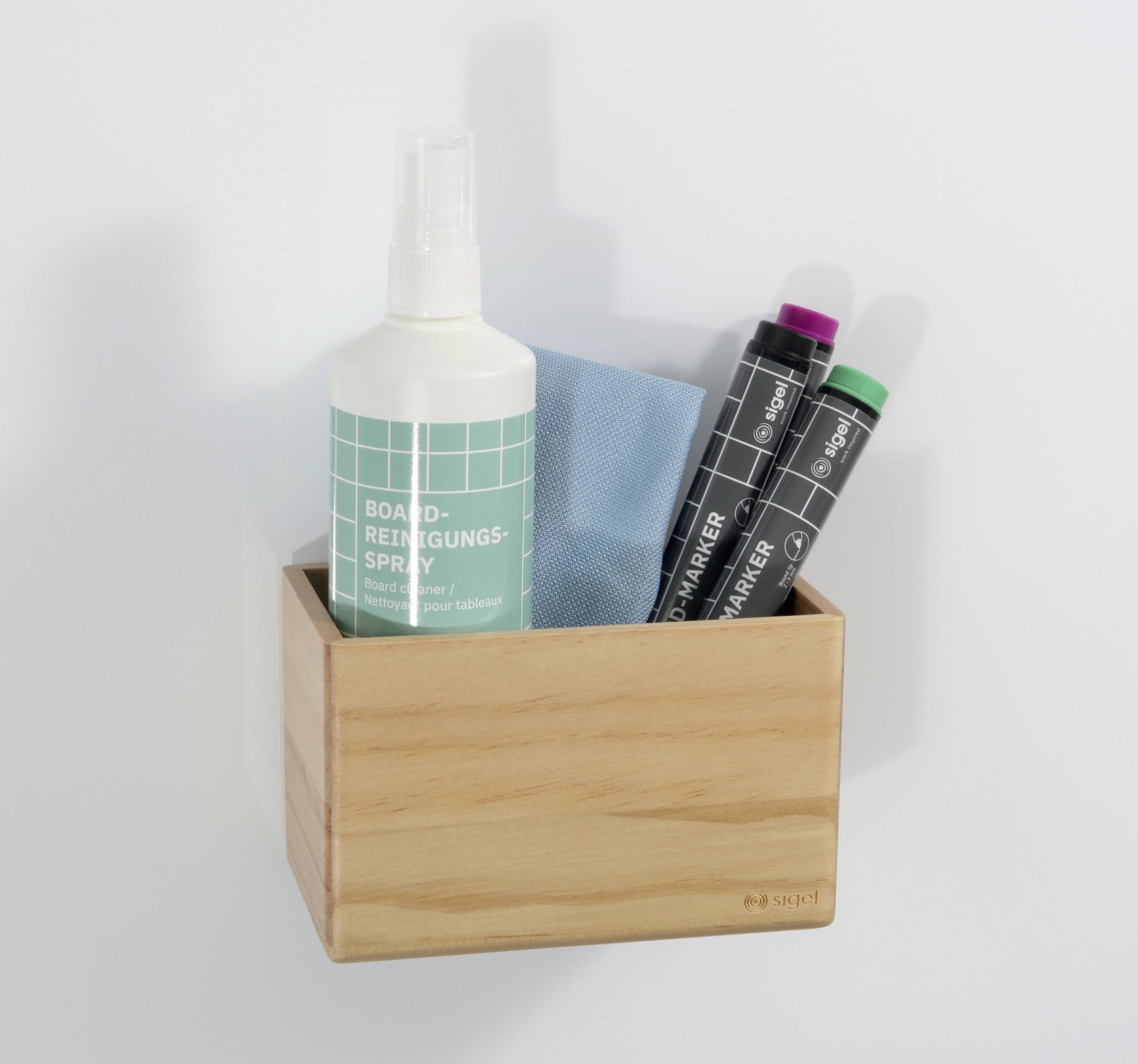 Ein Holzkasten enthält ein Reinigungs-Spray, ein blaues Tuch und zwei Tafelmarker. Sie sind an einer weißen Wand angebracht.