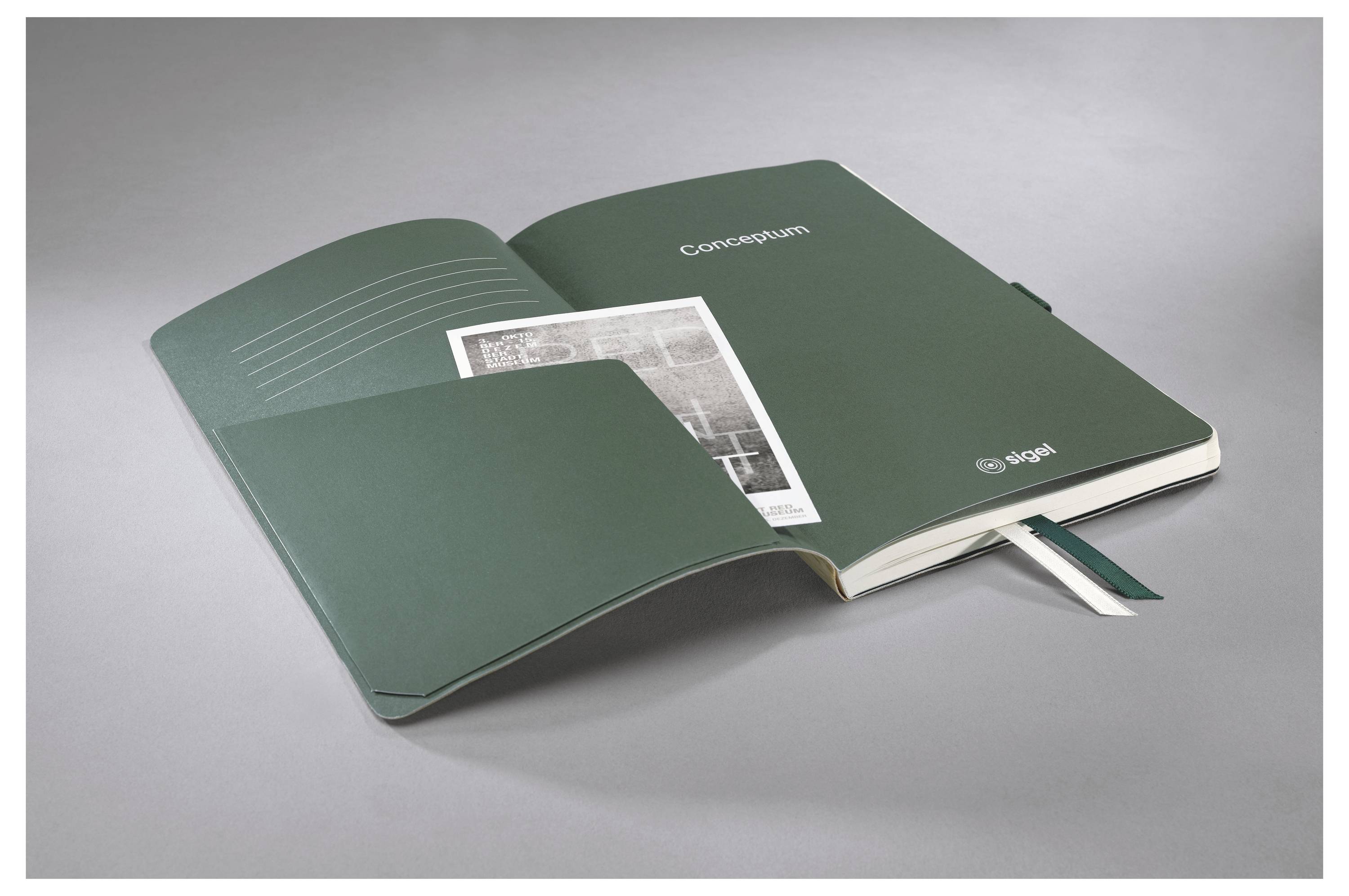 Öffnen Sie ein grünes Notizbuch mit dem Titel „Conclusiones" mit einer Fotoeinfügung und Bandlesezeichen, das auf einer grauen Oberfläche aufgeschlagen liegt.