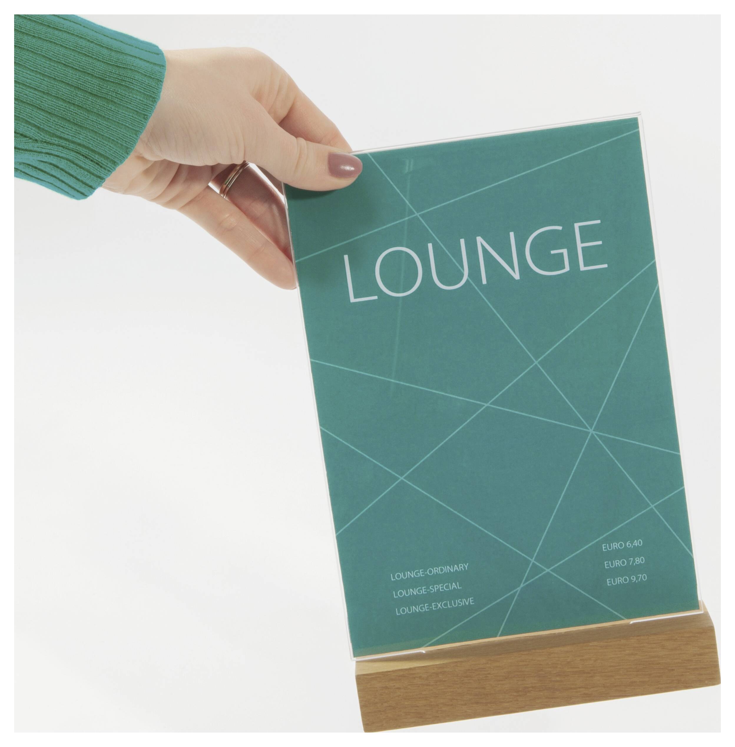 Hand hält ein blaugrünes „LOUNGE"-Booklet mit einer Holzbasis vor einem weißen Hintergrund, das einem Verzeichnis oder einer Speisekarte ähnelt.