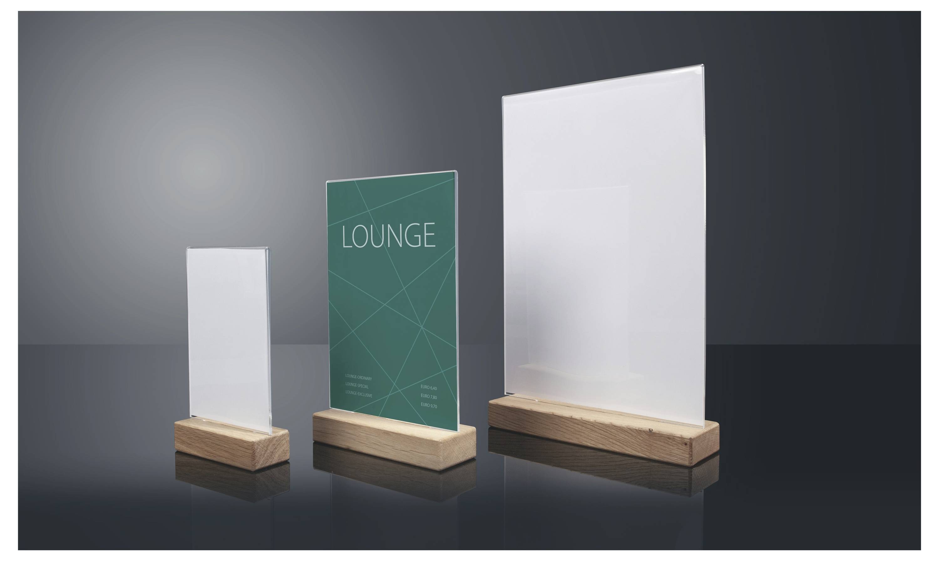 Drei Tischaufsteller in verschiedenen Größen, einschließlich eines blaugrünen Schildes mit der Aufschrift „LOUNGE", auf dunklem Hintergrund angezeigt.