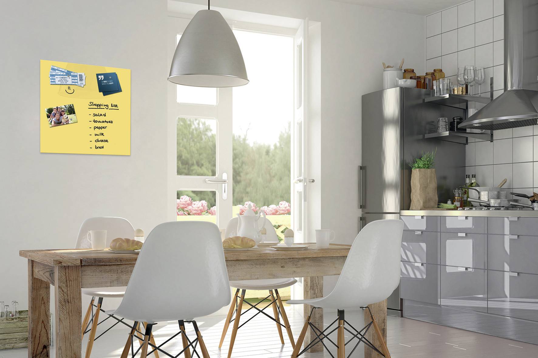 Eine moderne Küche mit einem Holztisch und weißen Stühlen. An der Wand hängt eine Tafel mit einer Einkaufsliste und einer Rezeptkarte.
