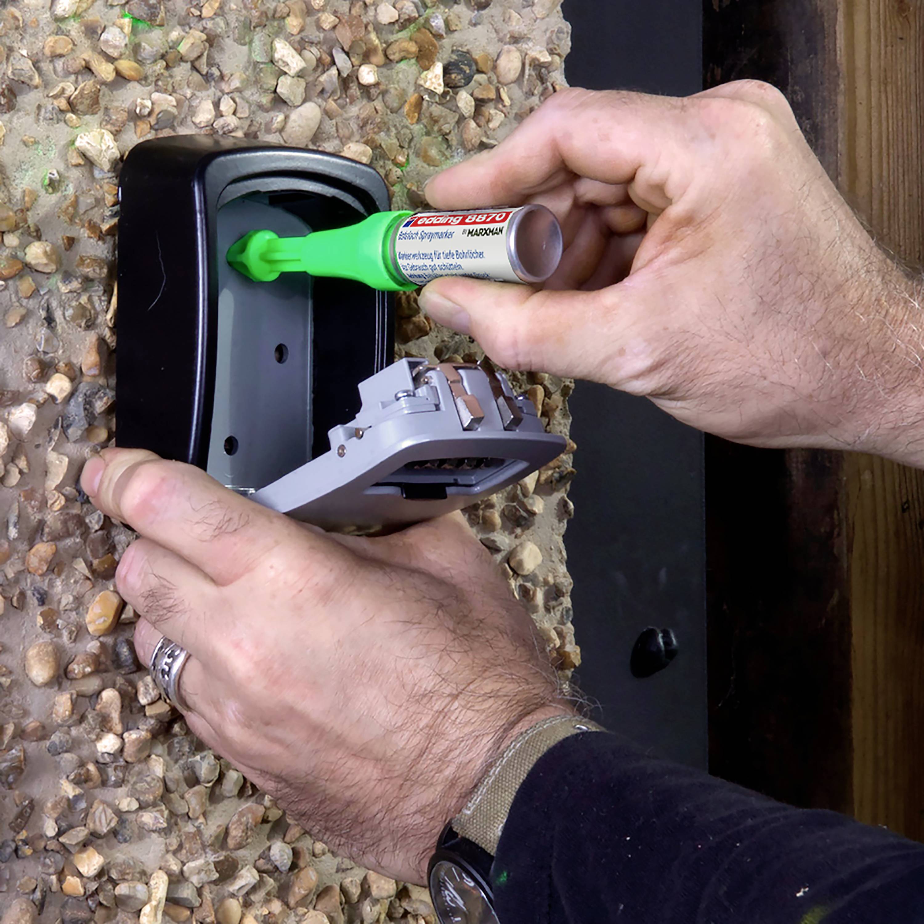 Eine Person füllt Klebstoff in einen an der Wand montierten Spender ein. Der Spender hat eine geöffnete Klappe.