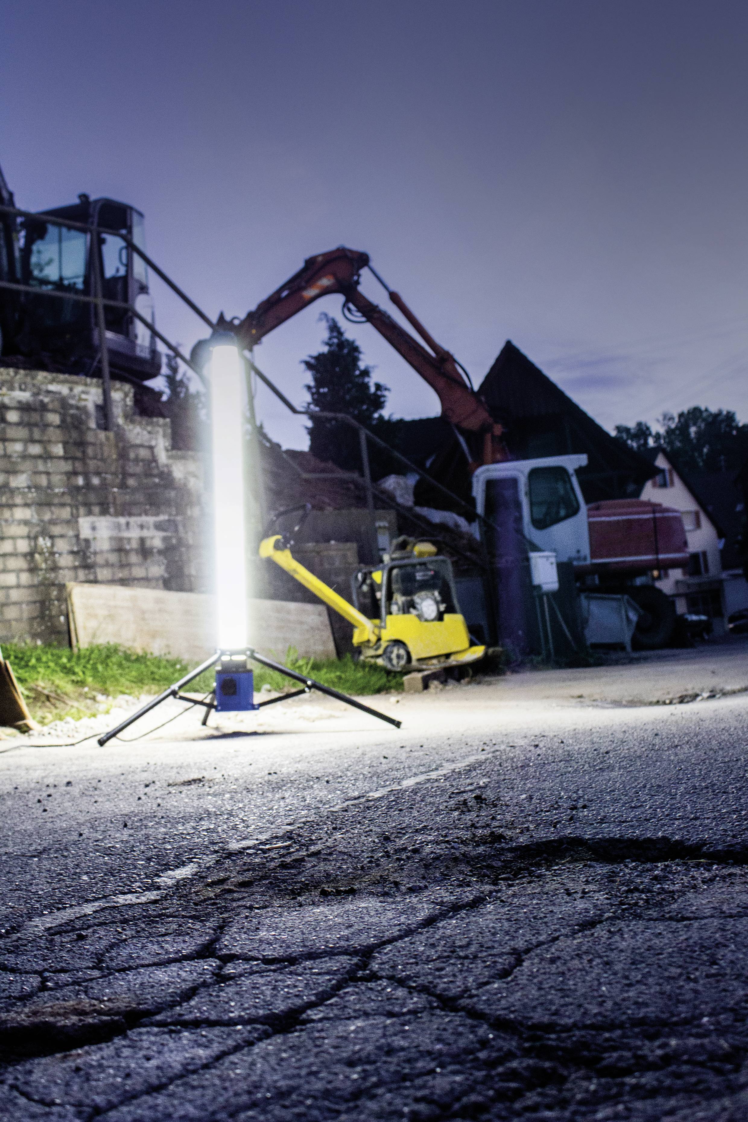 Nächtliche Baustelle mit hellem Scheinwerfer, Bagger, LKW und gerissenem Asphalt.
