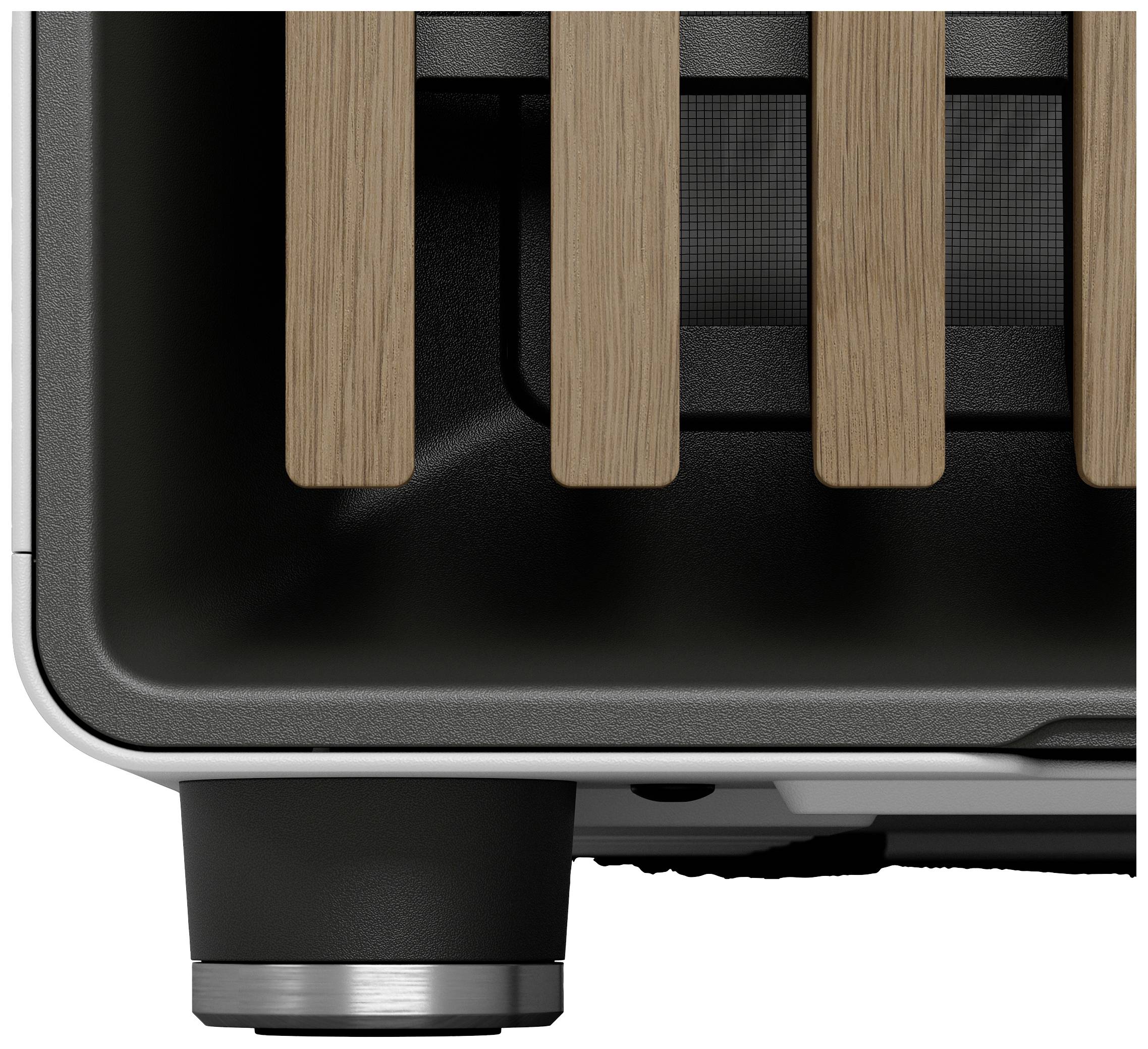 Ein Toaster mit schwarzen und hölzernen Elementen, teilweise sichtbar, fokussiert auf den unteren Teil und die Standfüße.