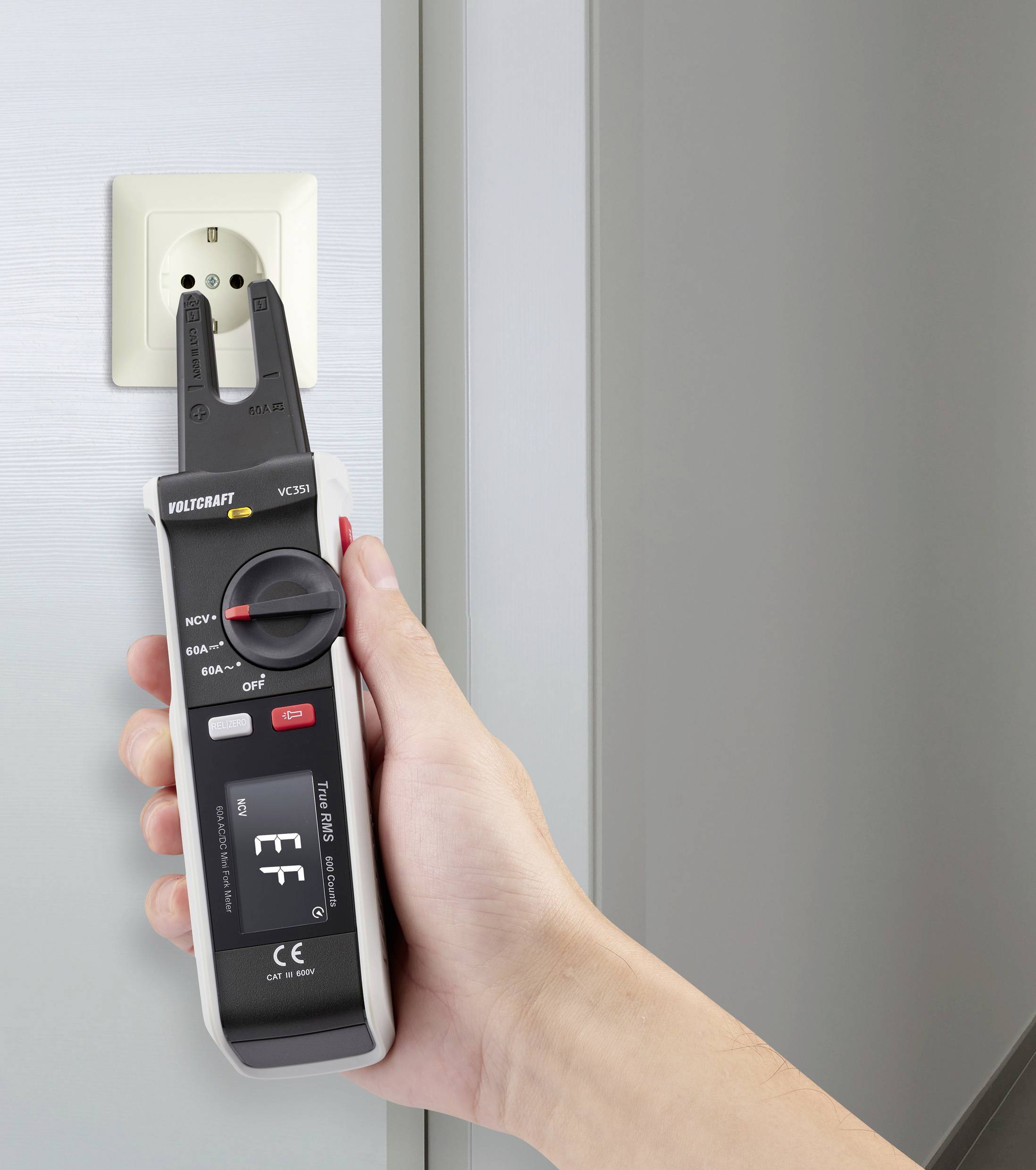 Eine Hand hält ein elektrisches Prüfgerät an einer Steckdose. Das Gerät zeigt den Status 'EF' an. Verschiedene Modi sind auswählbar.