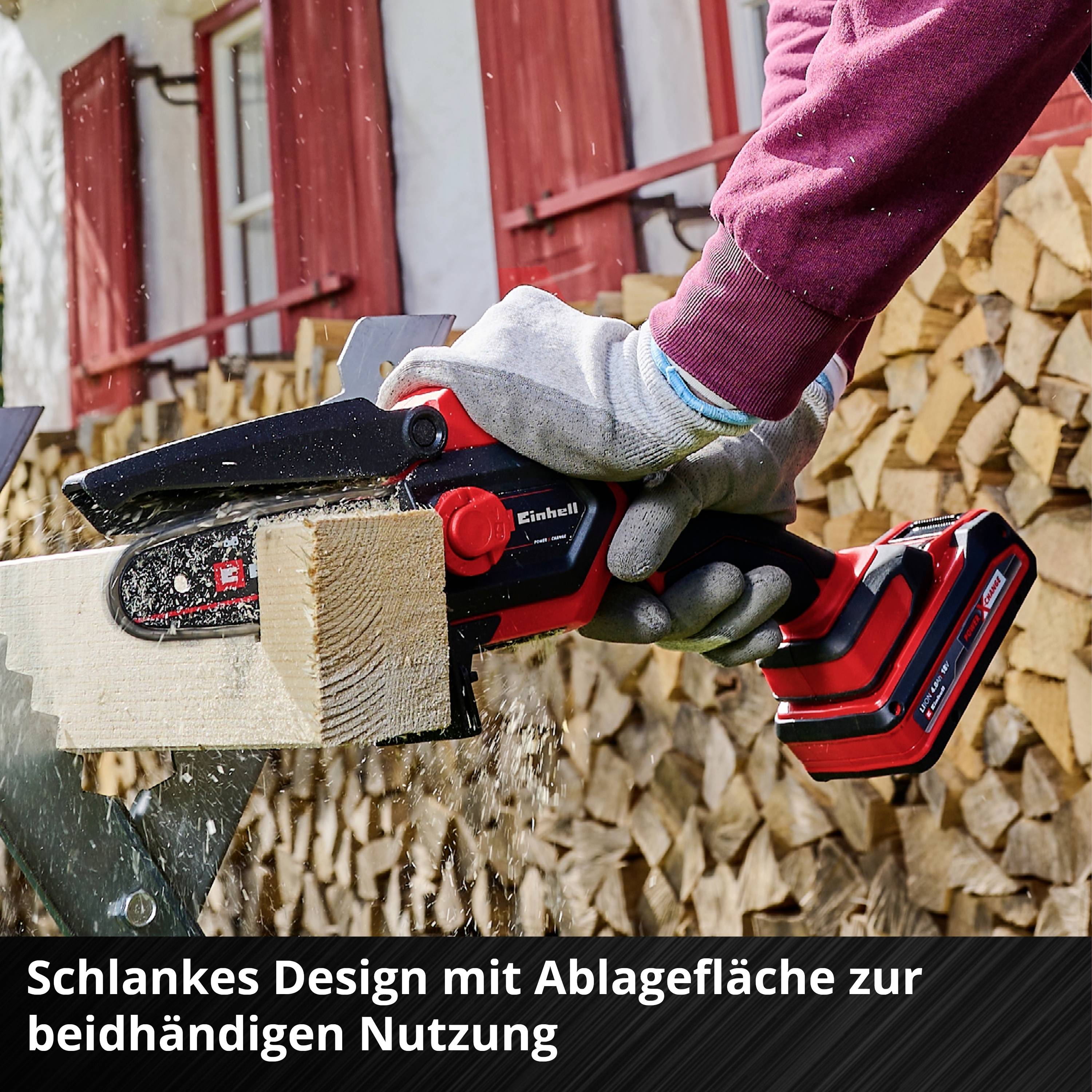 Eine Person sägt mit einer Akku-Kettensäge ein Holzstück. Im Hintergrund liegen gestapelte Holzscheite. Text im Bild: 'Schlankes Design mit Ablagefläche zur beidhändigen Nutzung'.