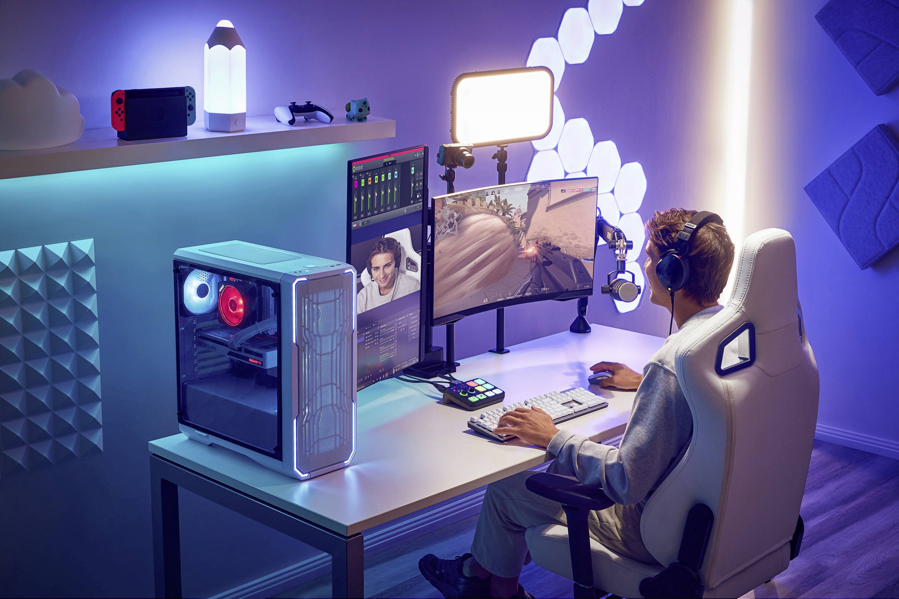 Person spielt Videospiel auf Computer mit zwei Bildschirmen, umgeben von LED-Leuchten und Gaming-Setup; Fokus auf Actionspiel.