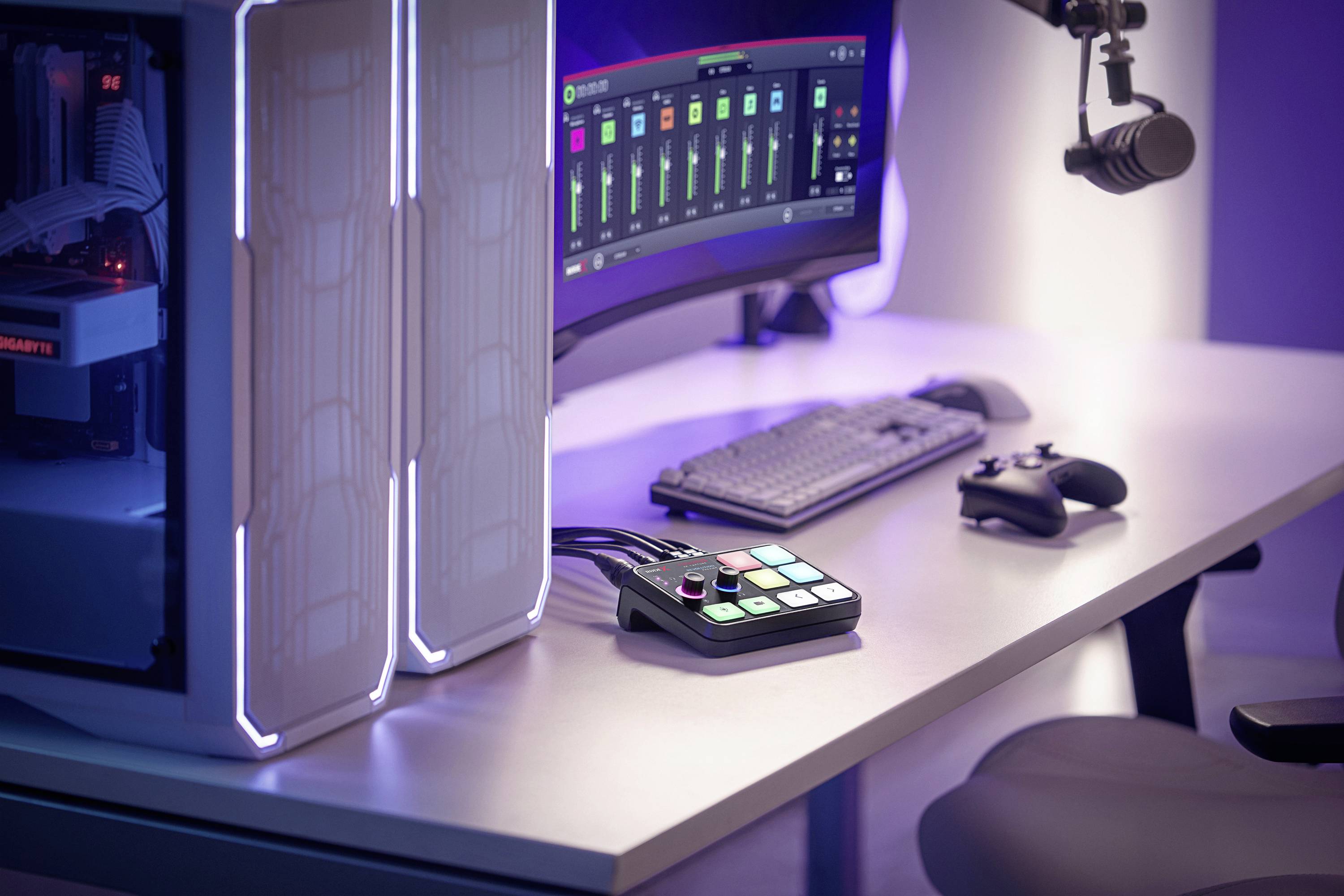 Ein moderner Computertisch mit großem Monitor, Tastatur, Mikrofon, Controller und Audio-Mischpult auf einem beleuchteten Schreibtisch.
