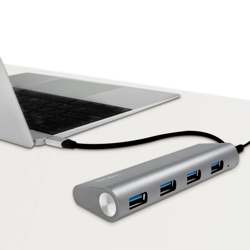 Ein Laptop ist mit einem USB-Hub verbunden, der vier USB-Ports bietet. Der Hub ist silberfarben und auf einem Tisch platziert.