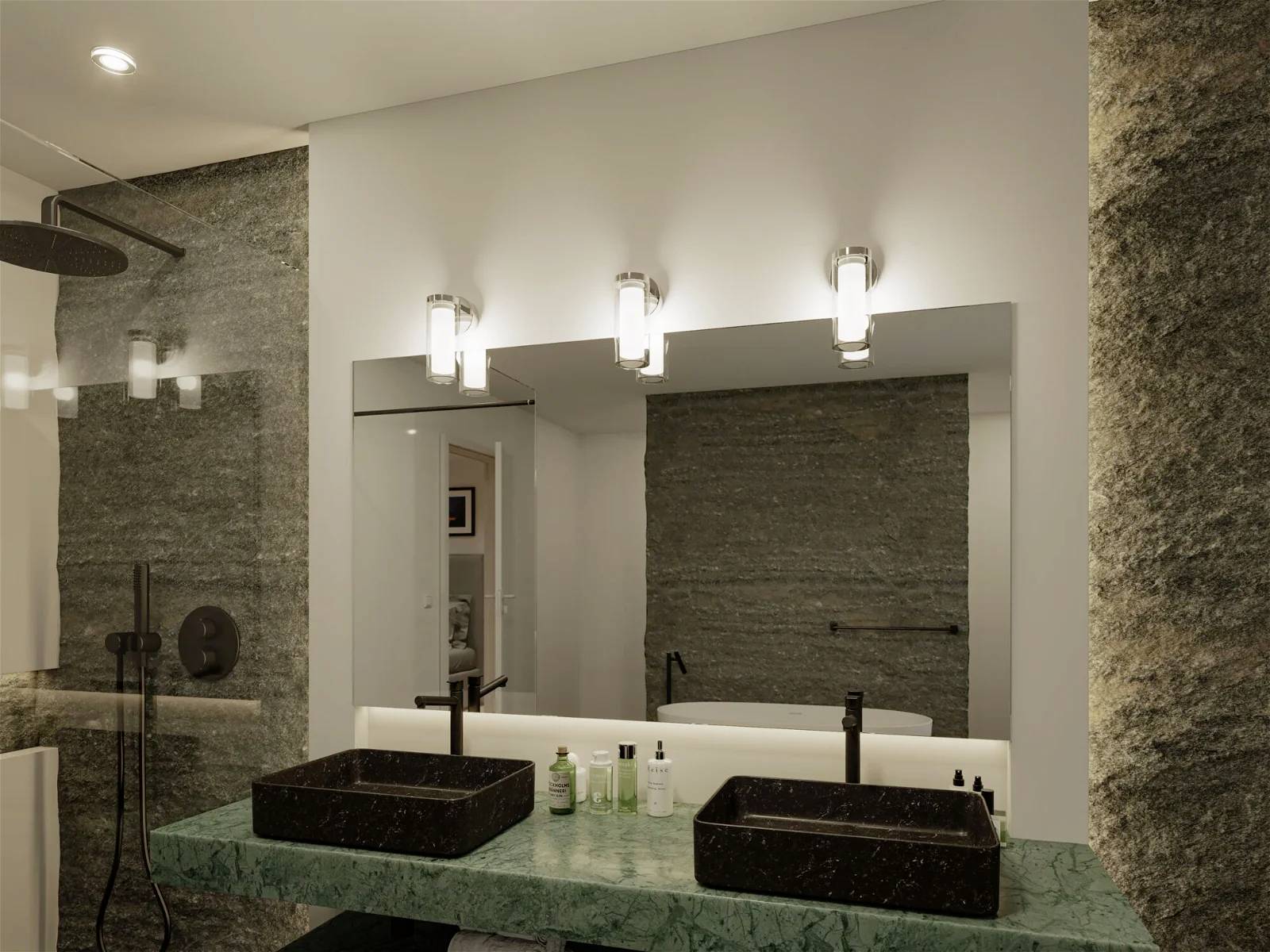 Modernes Badezimmer mit zwei schwarzen Waschbecken auf grünem Marmor, Spiegel und Beleuchtung. Wände aus grauem Stein.