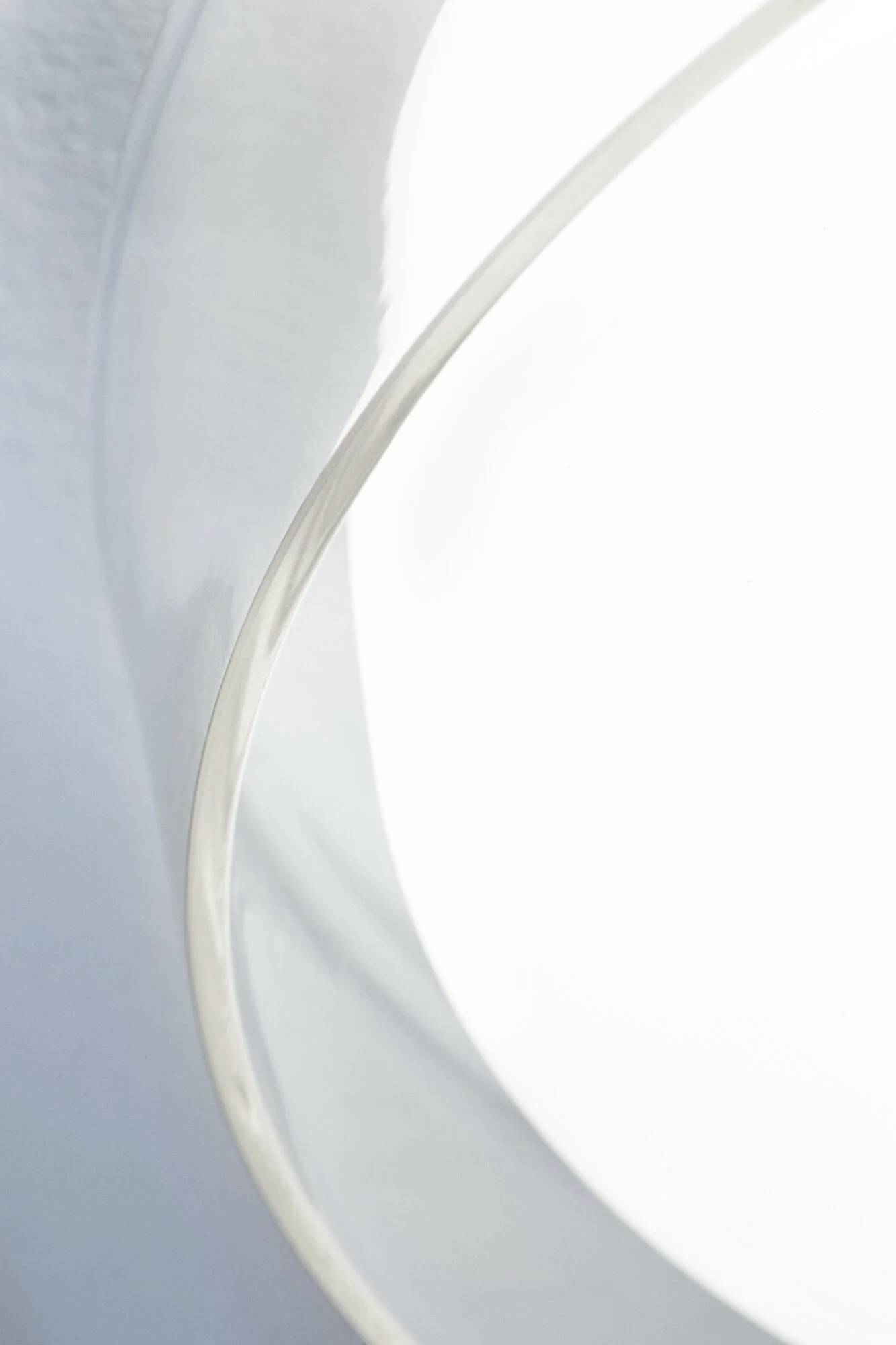 Ein abstraktes Bild zeigt zwei geschwungene, halbtransparente Formen in Weiß und Hellgrau, die sich überlappen.