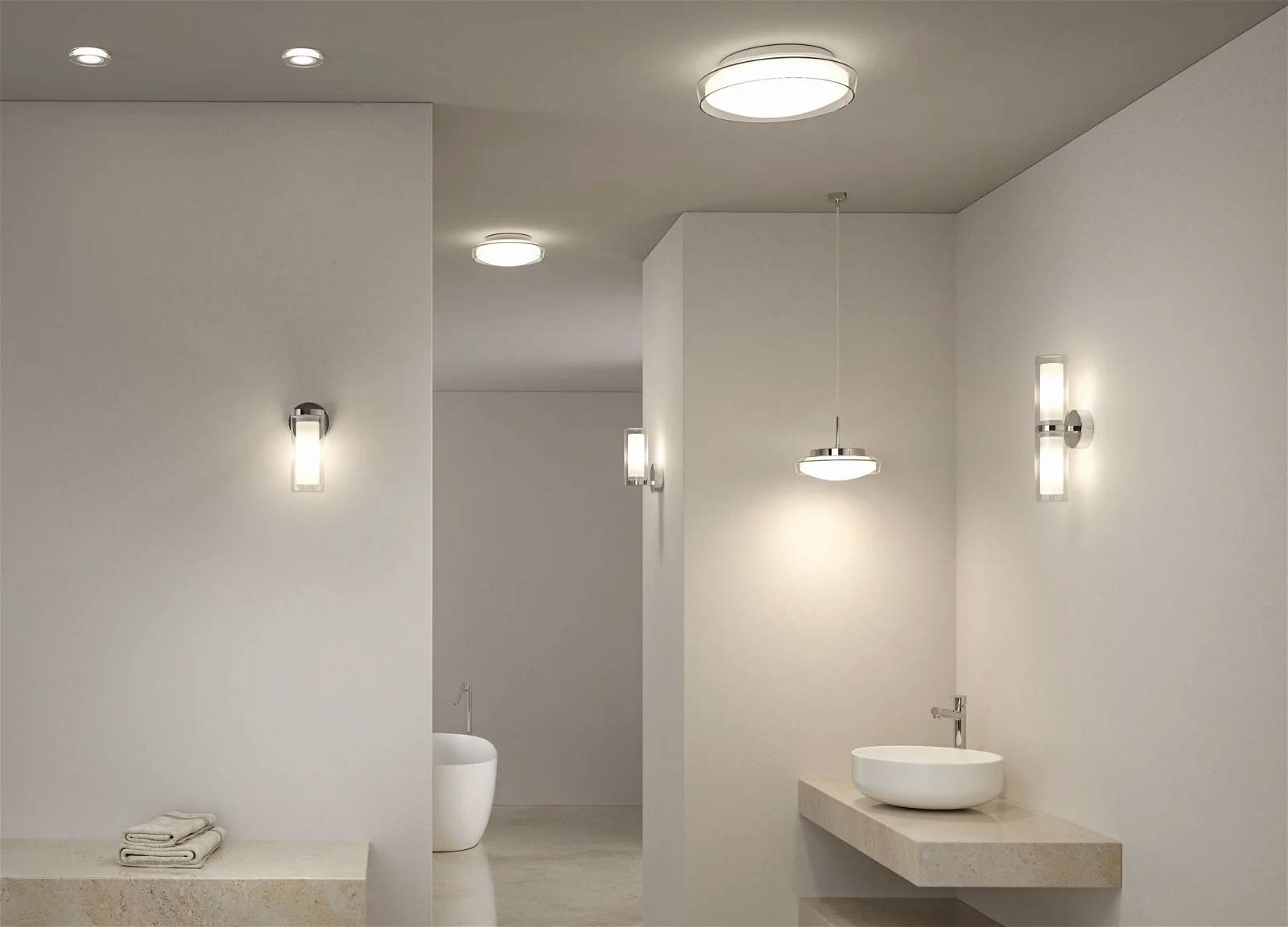 Modernes Badezimmer mit stilvoller Beleuchtung, Waschtisch mit Waschbecken rechts, freistehende Badewanne im Hintergrund.