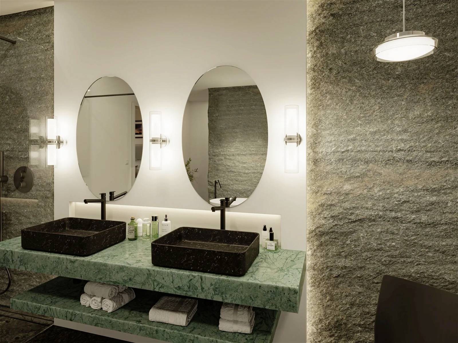 Modernes Badezimmer mit zwei ovalen Spiegeln, schwarzen rechteckigen Waschbecken und grüner Marmorplatte. Neutrale Beleuchtung.
