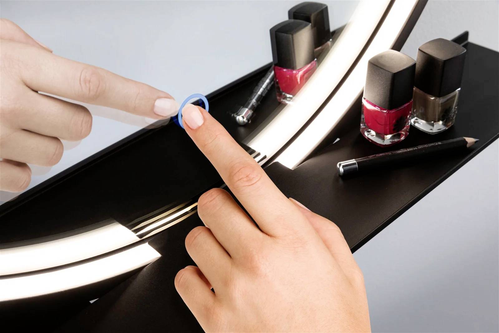 Zwei Hände mit Nagellack, Spiegelbild, verschiedene Nagellackfarben im Hintergrund, eine Hand trägt roten Nagellack auf.