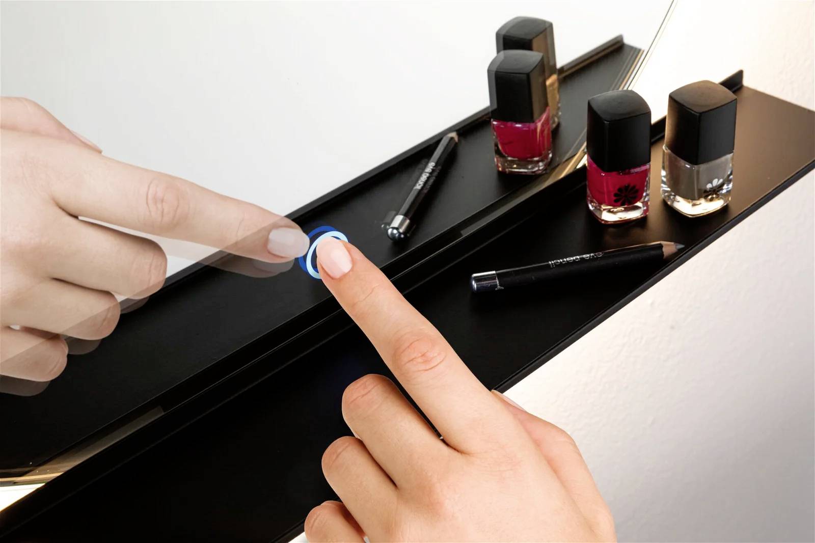 Finger drückt auf Schalter eines beleuchteten Schminkspiegels, um das Licht ein- oder auszuschalten. Daneben Nagellackfläschchen.