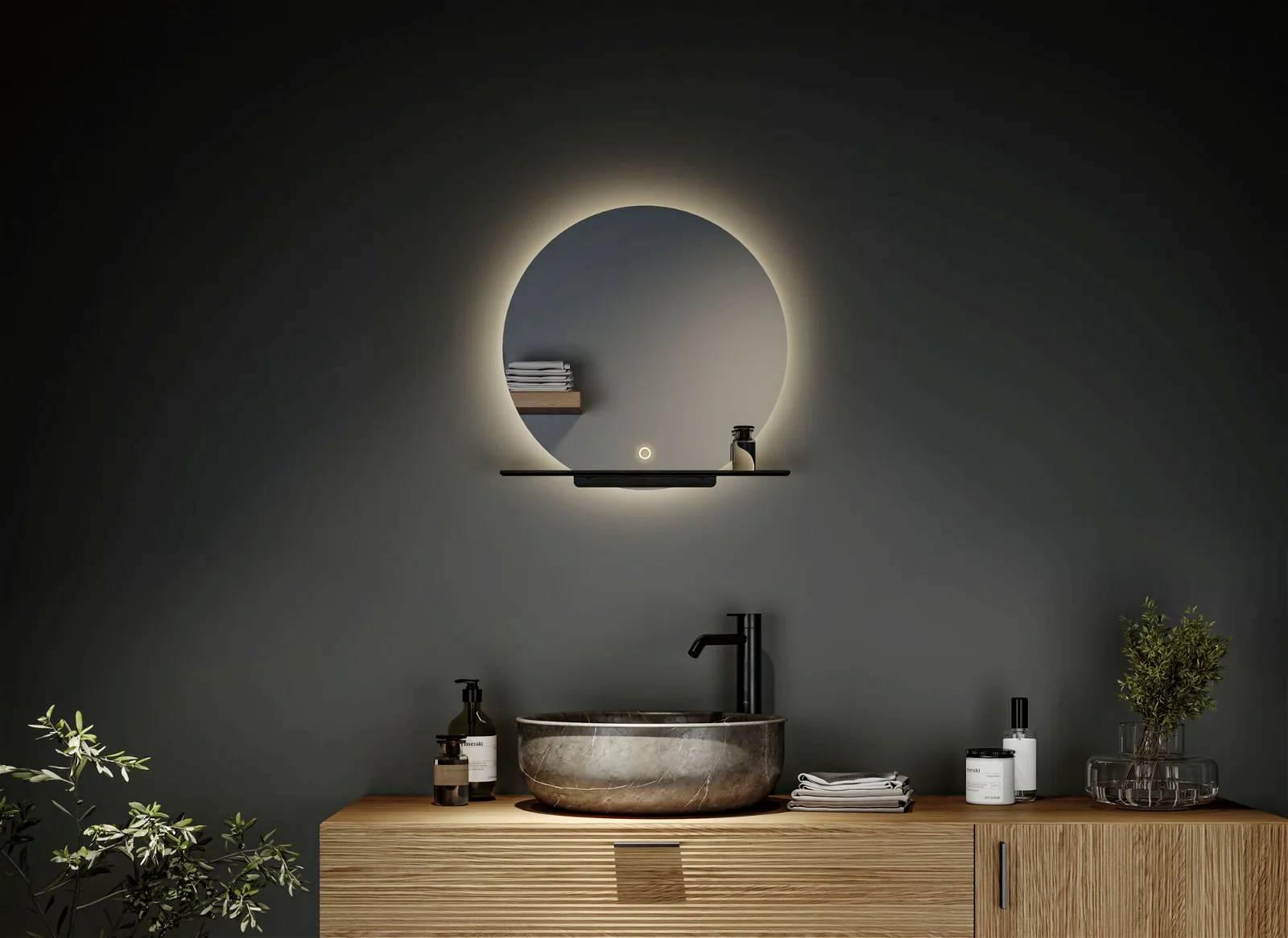 Moderne Badezimmer-Einrichtung: beleuchteter runder Spiegel über einem Waschbecken auf Holztisch, umgeben von Seifenspendern und Pflanzen.