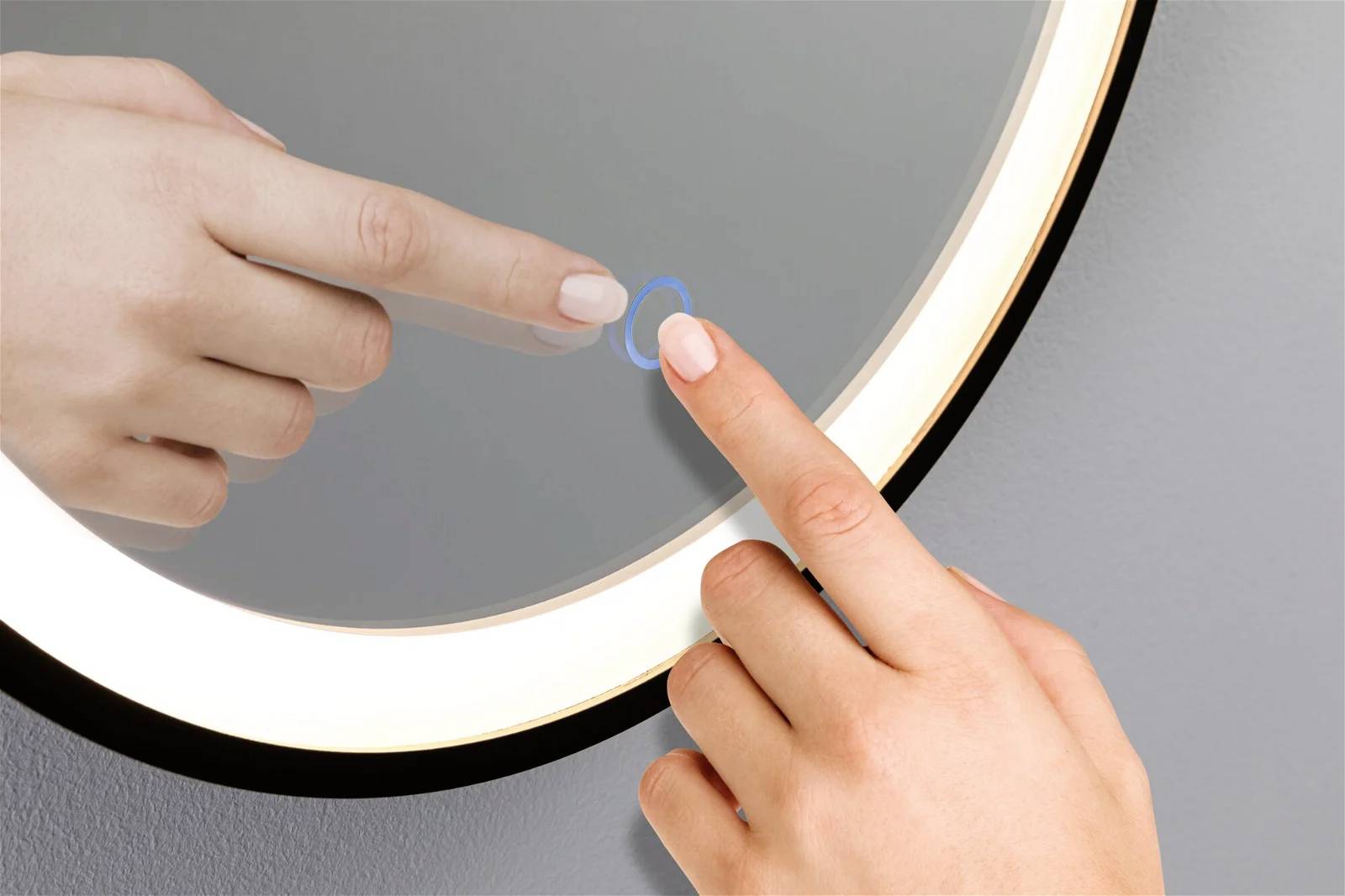 Eine Hand berührt mit dem Zeigefinger einen beleuchteten runden Spiegel, offenbar zum Aktivieren einer Touch-Funktion.
