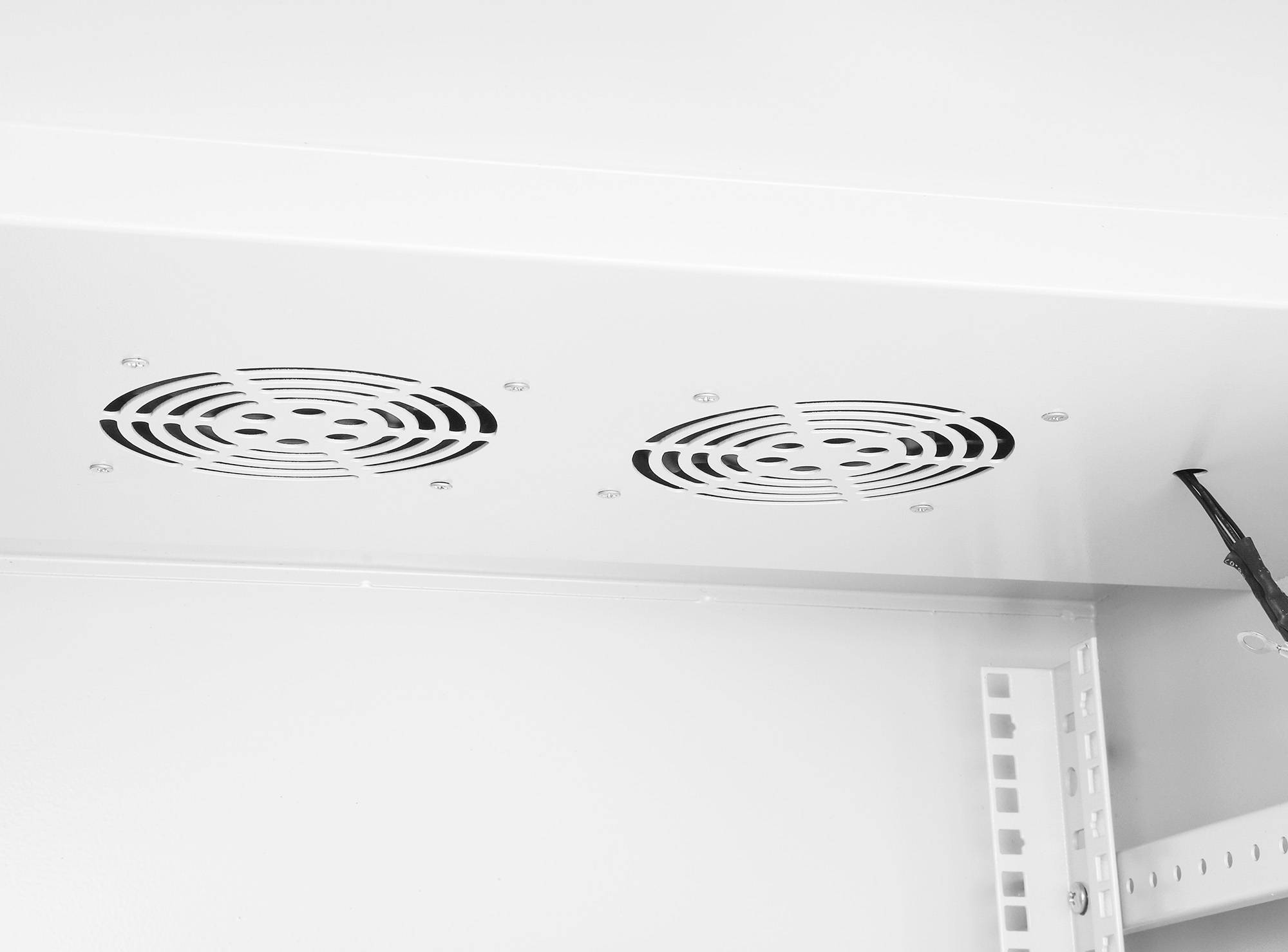 Weiße Oberfläche mit zwei runden Lüftungsgittern und einem Kabel, das an der Seite hängt.