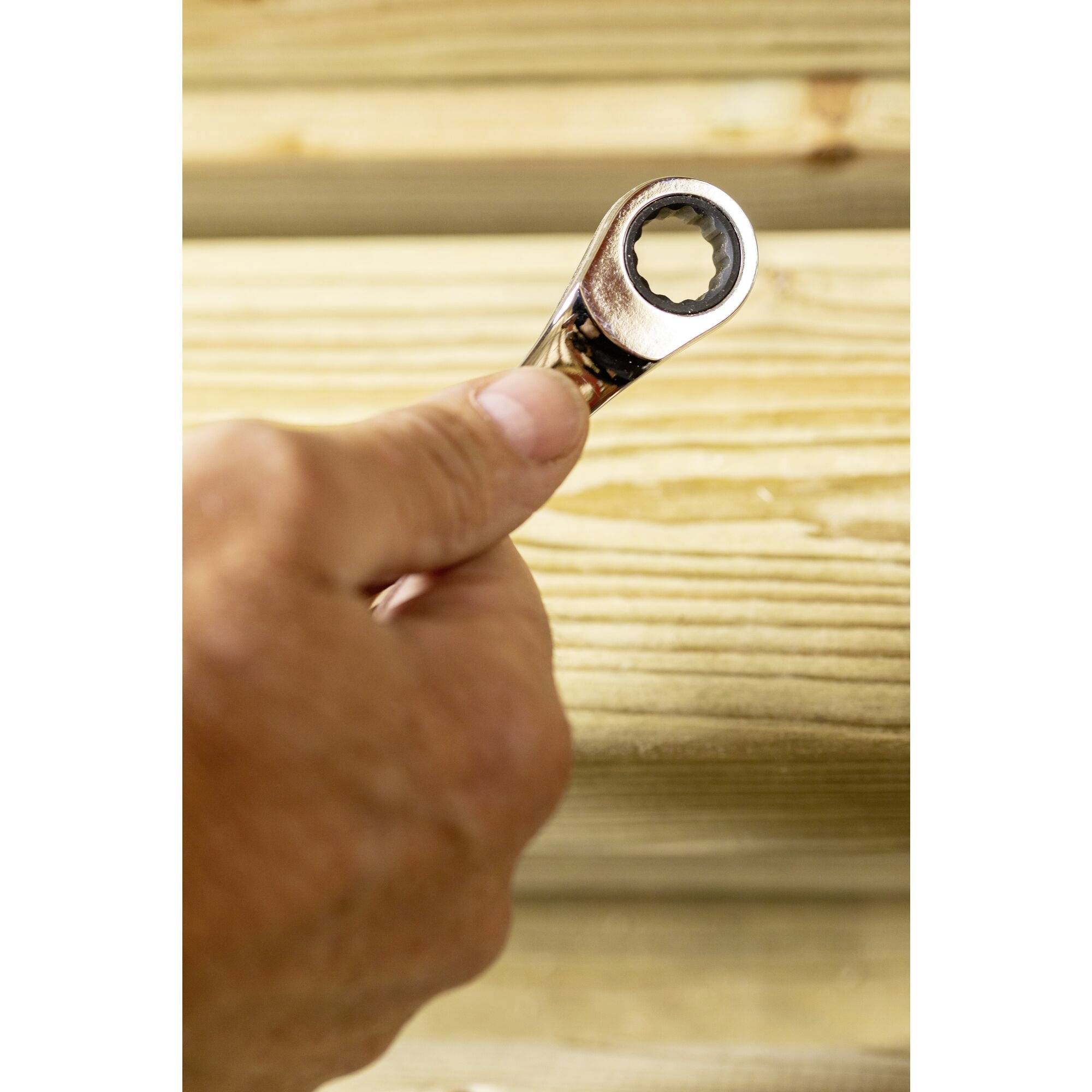 Eine Hand hält einen Ringschlüssel, um einen Holzstapel festzuziehen.