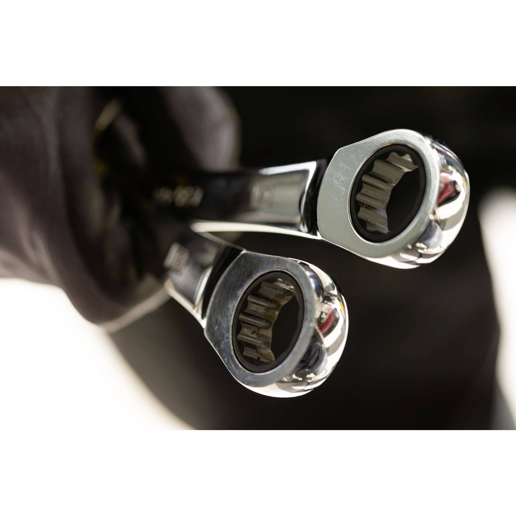 Eine Hand hält zwei silberne Maulschlüssel, bereit zum Einsatz in einer mechanischen Reparatur.