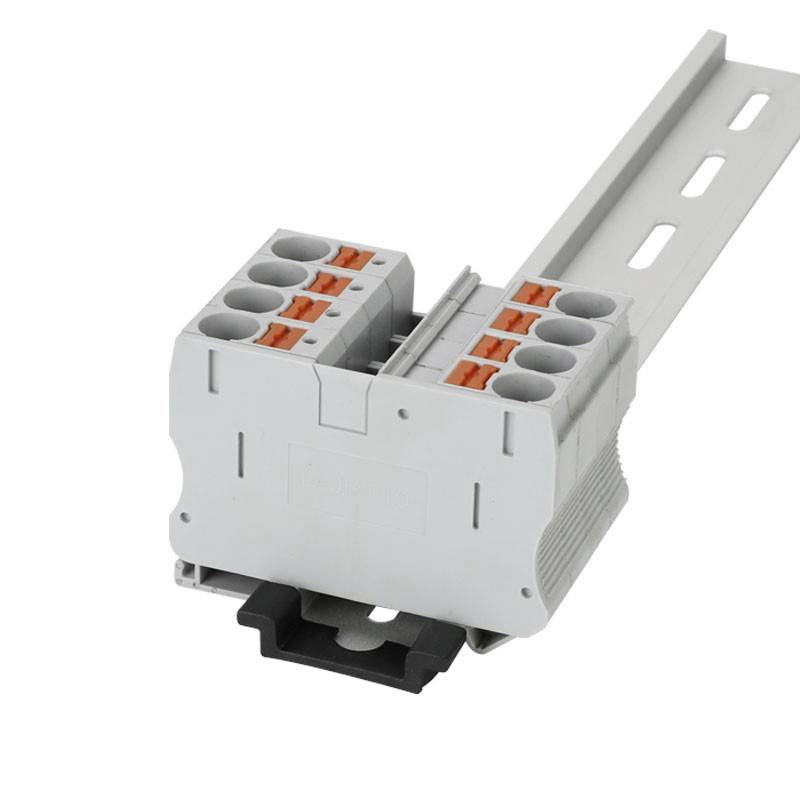 Eine graue elektrische Anschlussklemme mit mehreren Steckplätzen, montiert auf einer Hutschiene, zur Verdrahtung in Elektroschränken.